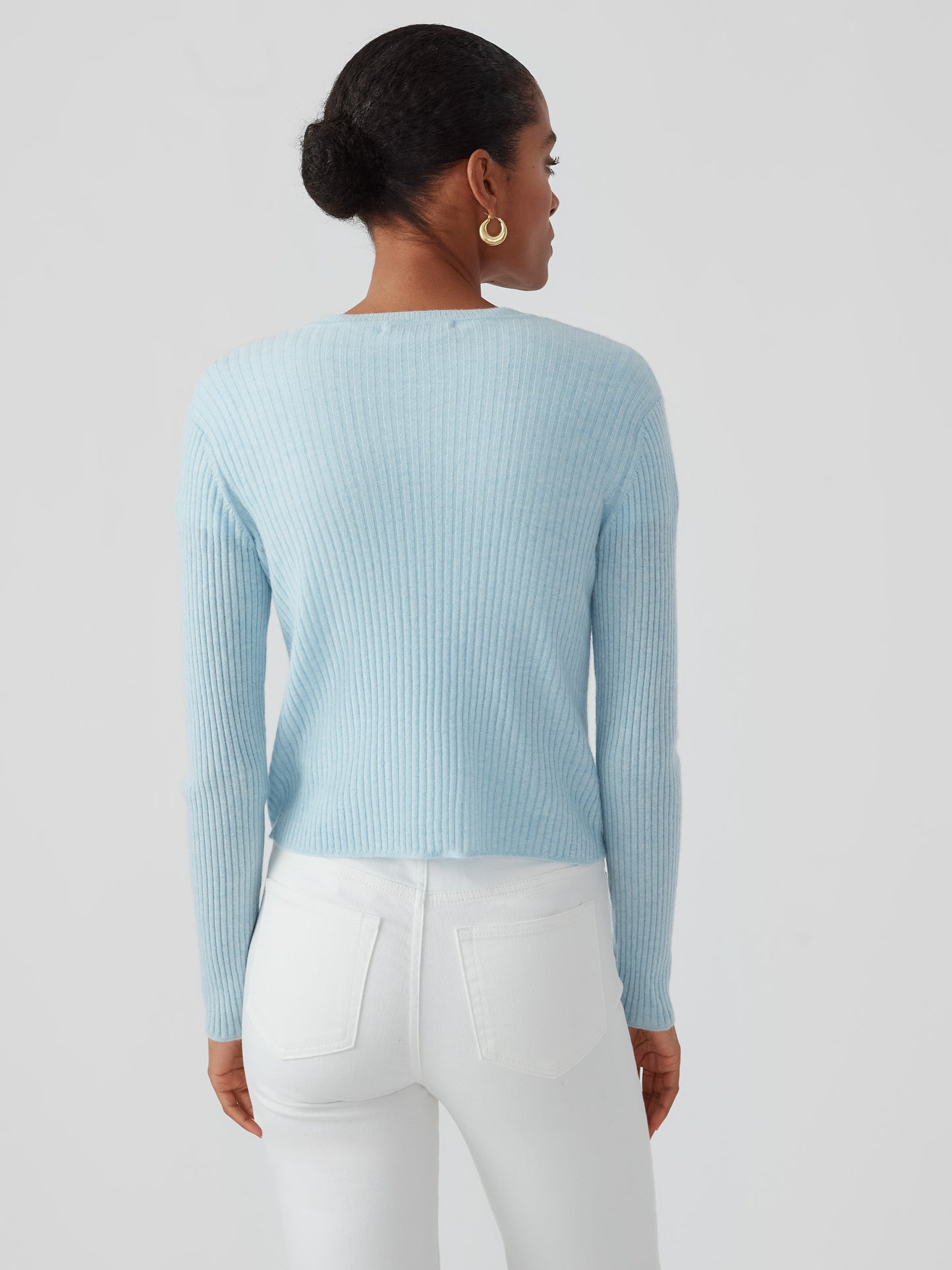 A woman models the Imogen Cashmere Cardigan by J.McLaughlin in a soft baby blue hue, showcasing its effortlessly stylish, enduring design crafted from innovative fabrics for a legacy of timeless fashion. A destination for defining style. Life, Well-Lived.