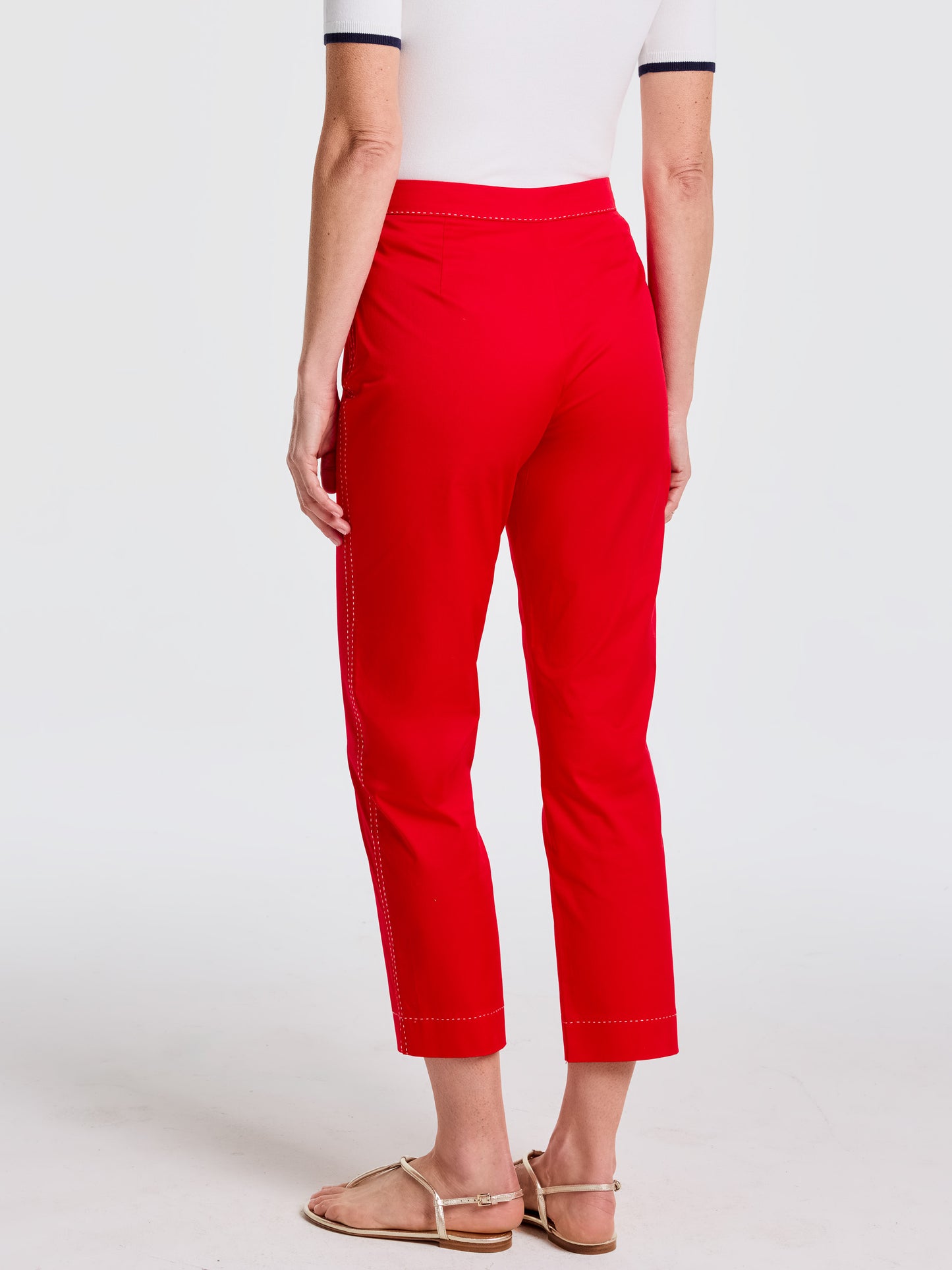 Back view of a woman wearing vibrant red Betina Pants by J.McLaughlin paired with neutral sandals and a white top, showcasing effortlessly stylish and enduring designs in a legacy of timeless fashion. A destination for defining style. Life, Well-Lived.