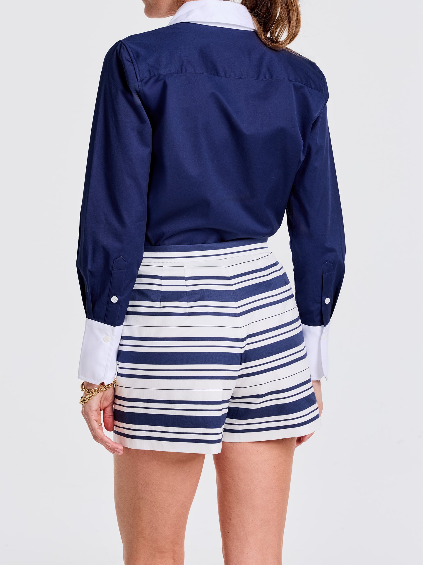 Woman wearing Emily Shorts in Mariner Stripe by J.McLaughlin, paired with a navy blouse featuring white cuffs, showcasing effortlessly stylish and enduring designs for a destination of defining style. Life, Well-Lived.