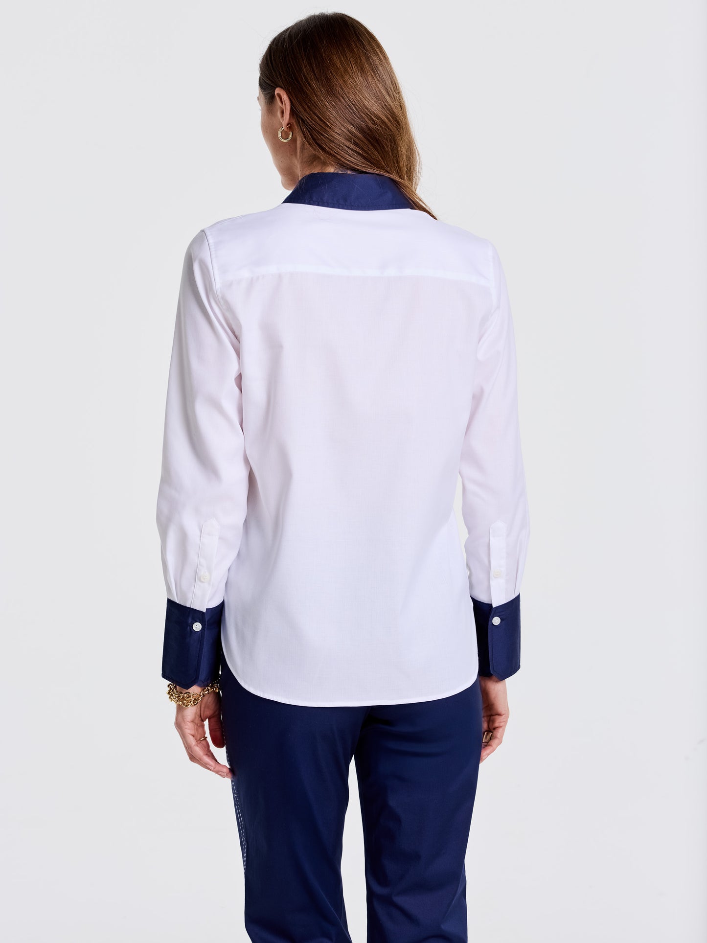 Woman seen from behind wearing a Karla Shirt by J.McLaughlin featuring white fabric with navy collar and cuffs, paired with navy pants, showcasing effortlessly stylish, enduring designs and a legacy of timeless fashion. A destination for defining style. Life, Well-Lived.