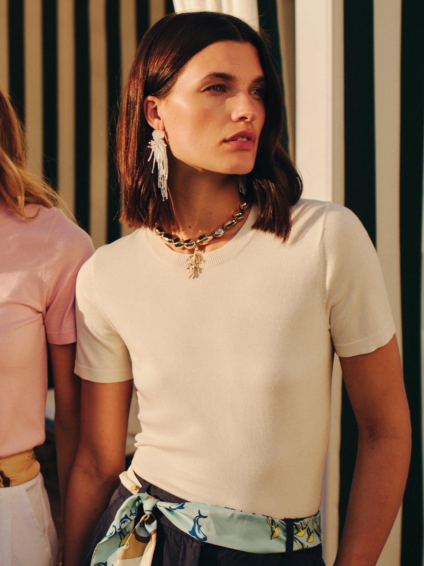Woman wearing Beaded Tassel Earrings paired with a cream top and patterned scarf belt, showcasing J.McLaughlin's effortlessly stylish, enduring designs and legacy of timeless fashion.
