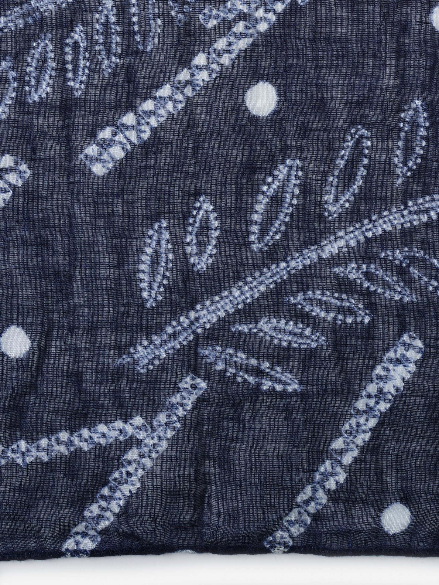 Close-up of the blue fabric with white leaf and dot patterns from the Men's Linen Scarf in Shibori Leaves by J.McLaughlin, showcasing effortlessly stylish, enduring designs and innovative fabrics.