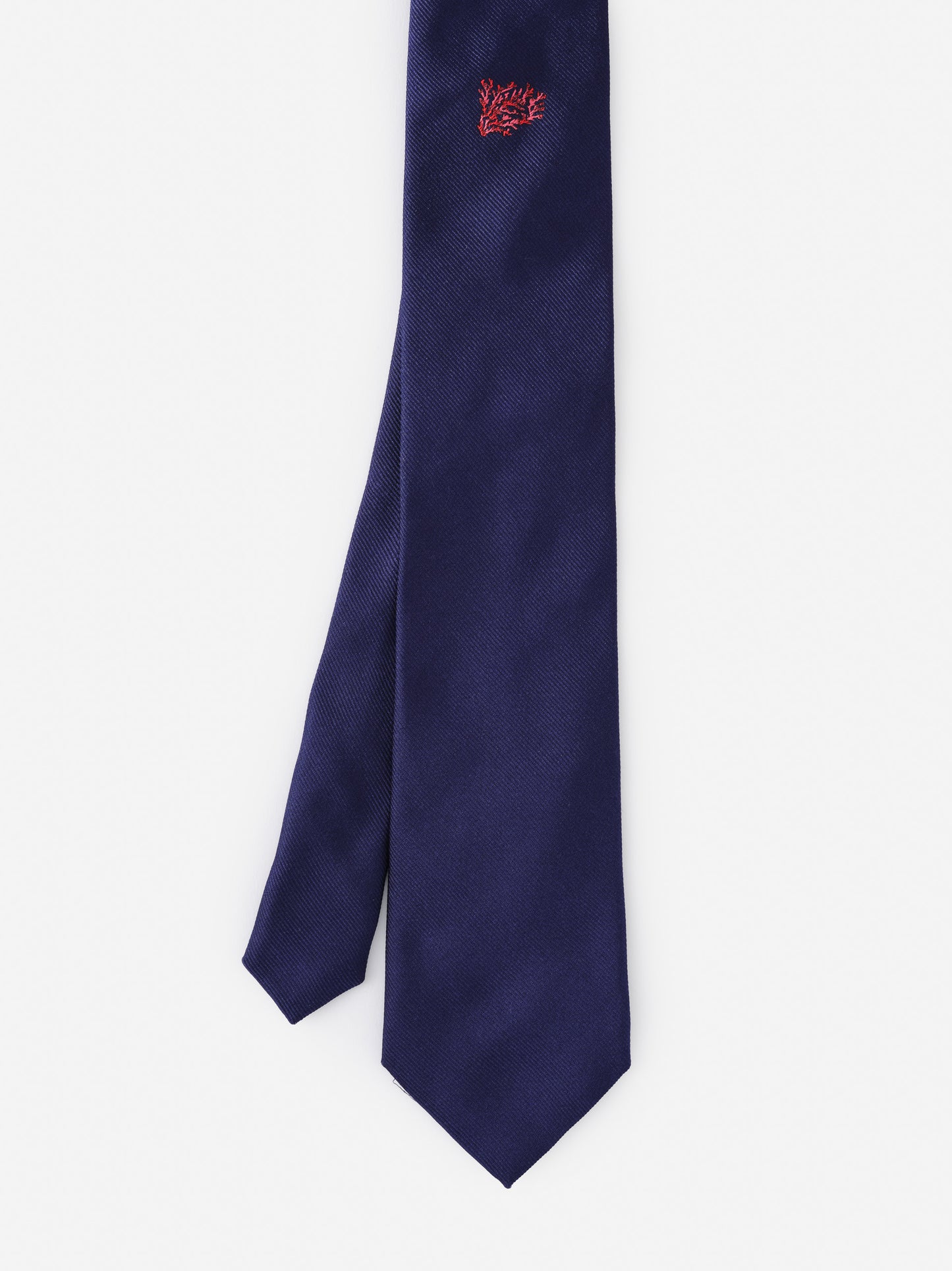 A J.McLaughlin Silk Tie in Coral Cay Texture in deep navy with a small coral embroidered detail, showcasing effortlessly stylish, enduring designs and innovative fabrics for a legacy of timeless fashion.