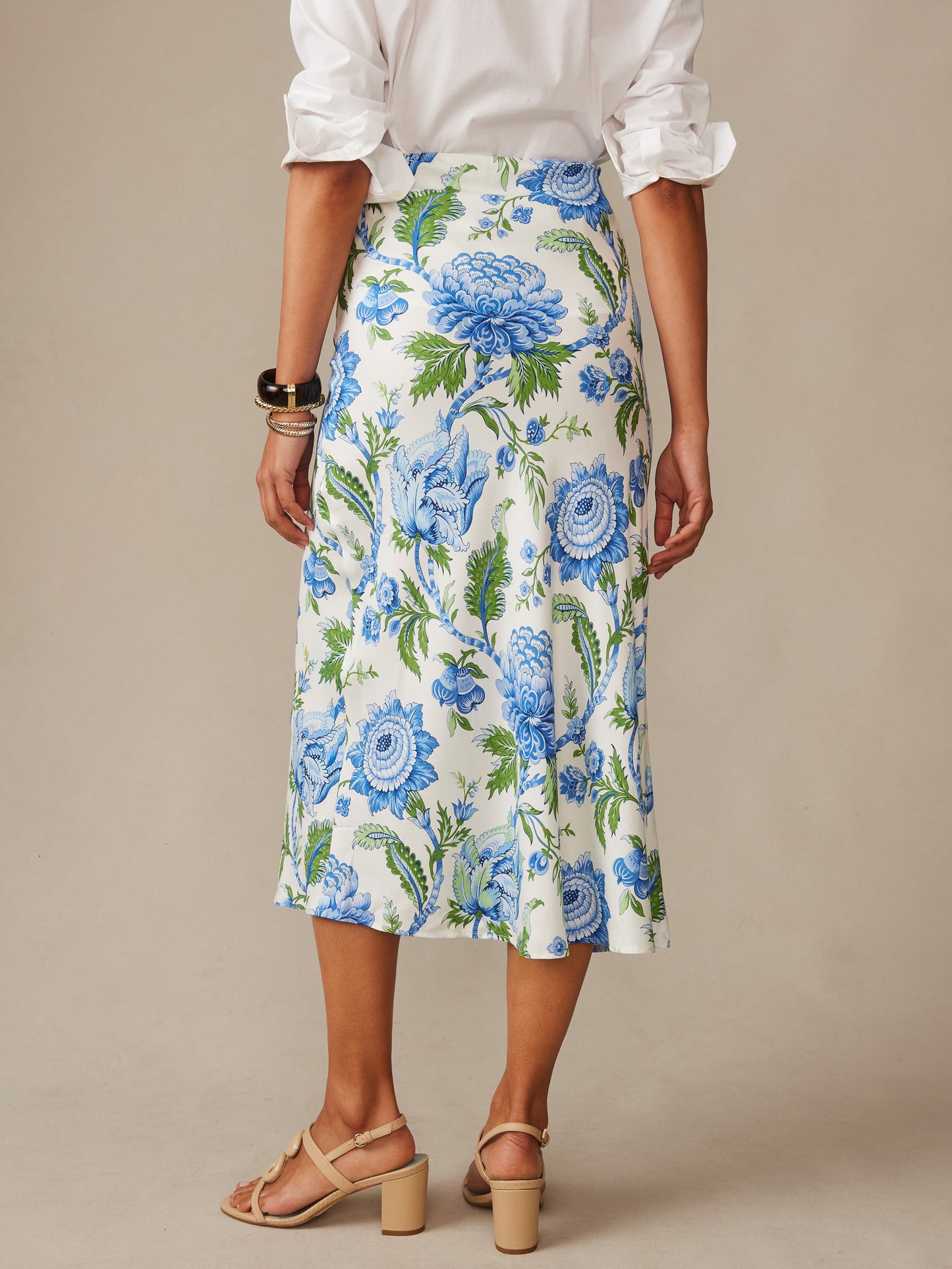 A woman models the Adelyn Silk Blend Skirt in Cerulean Garden Bias by J.McLaughlin, featuring a flowing floral pattern in blue and green, embodying effortlessly stylish, enduring designs and innovative fabrics for a destination for defining style. Life, Well-Lived.