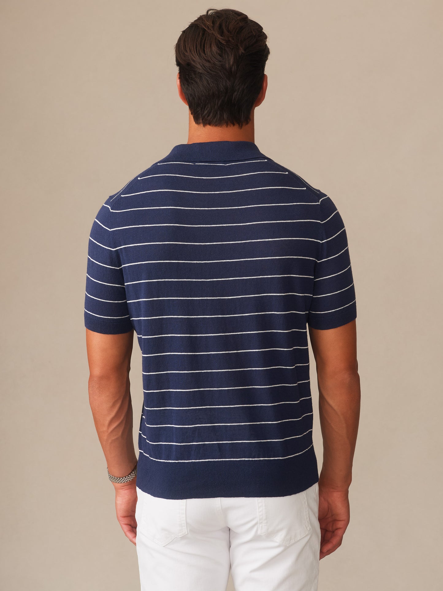 Man wearing a navy and white striped Amalfi Linen Blend Polo in Stripe by J.McLaughlin, showcasing effortlessly stylish design and innovative fabrics in a timeless, enduring look.