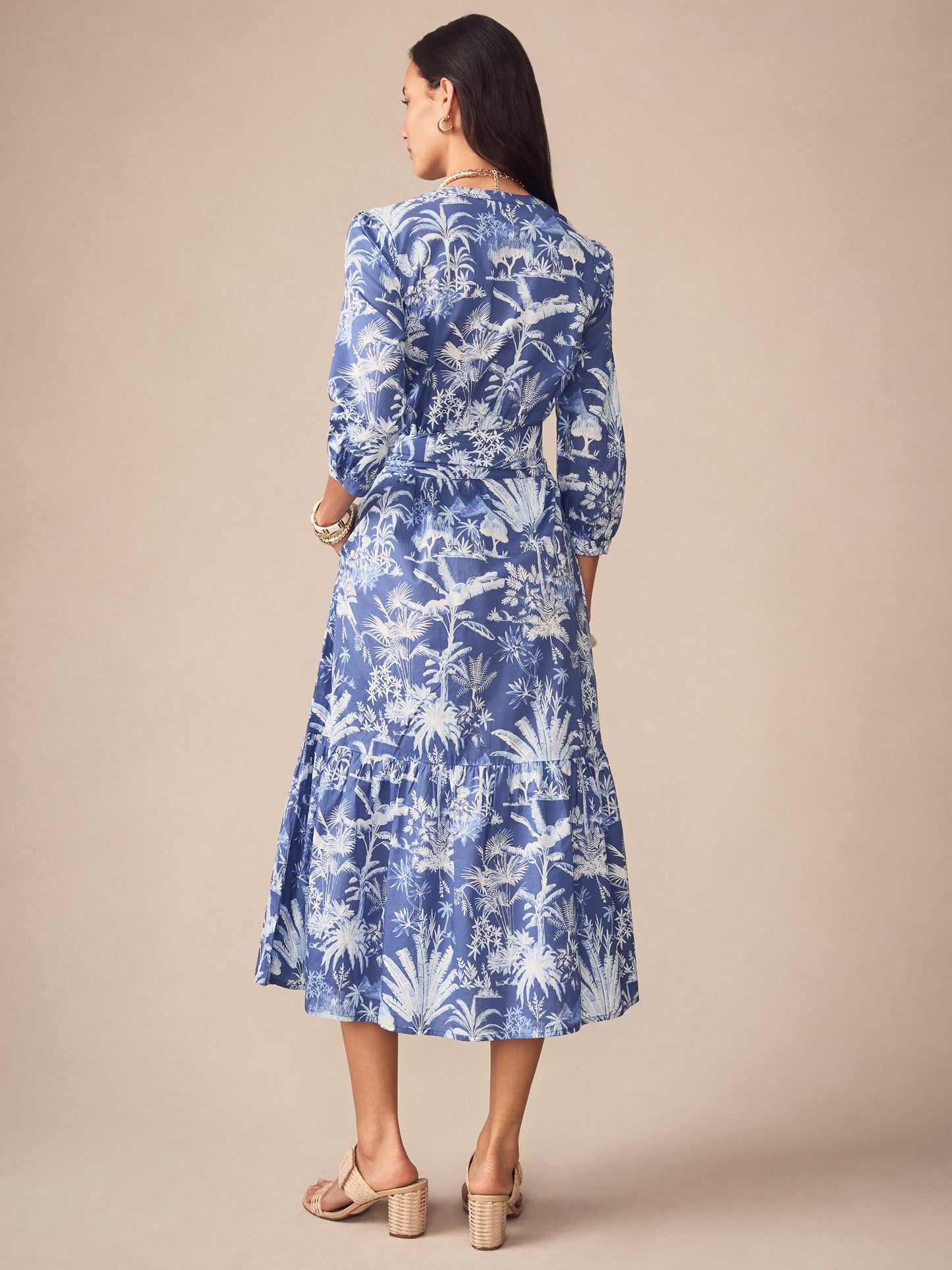 A woman wearing the Cerina Dress in Garden Isle by J.McLaughlin, featuring an effortlessly stylish blue and white botanical print dress with three-quarter sleeves and a tiered skirt, embodying enduring designs and a legacy of timeless fashion. A destination for defining style. Life, Well-Lived.