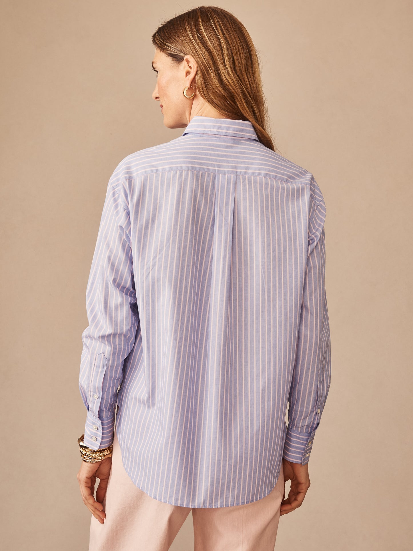Woman seen from behind wearing a Finn Shirt in Stripe by J.McLaughlin, featuring a classic blue and pink striped pattern, reflecting effortlessly stylish, enduring designs for a life well-lived.