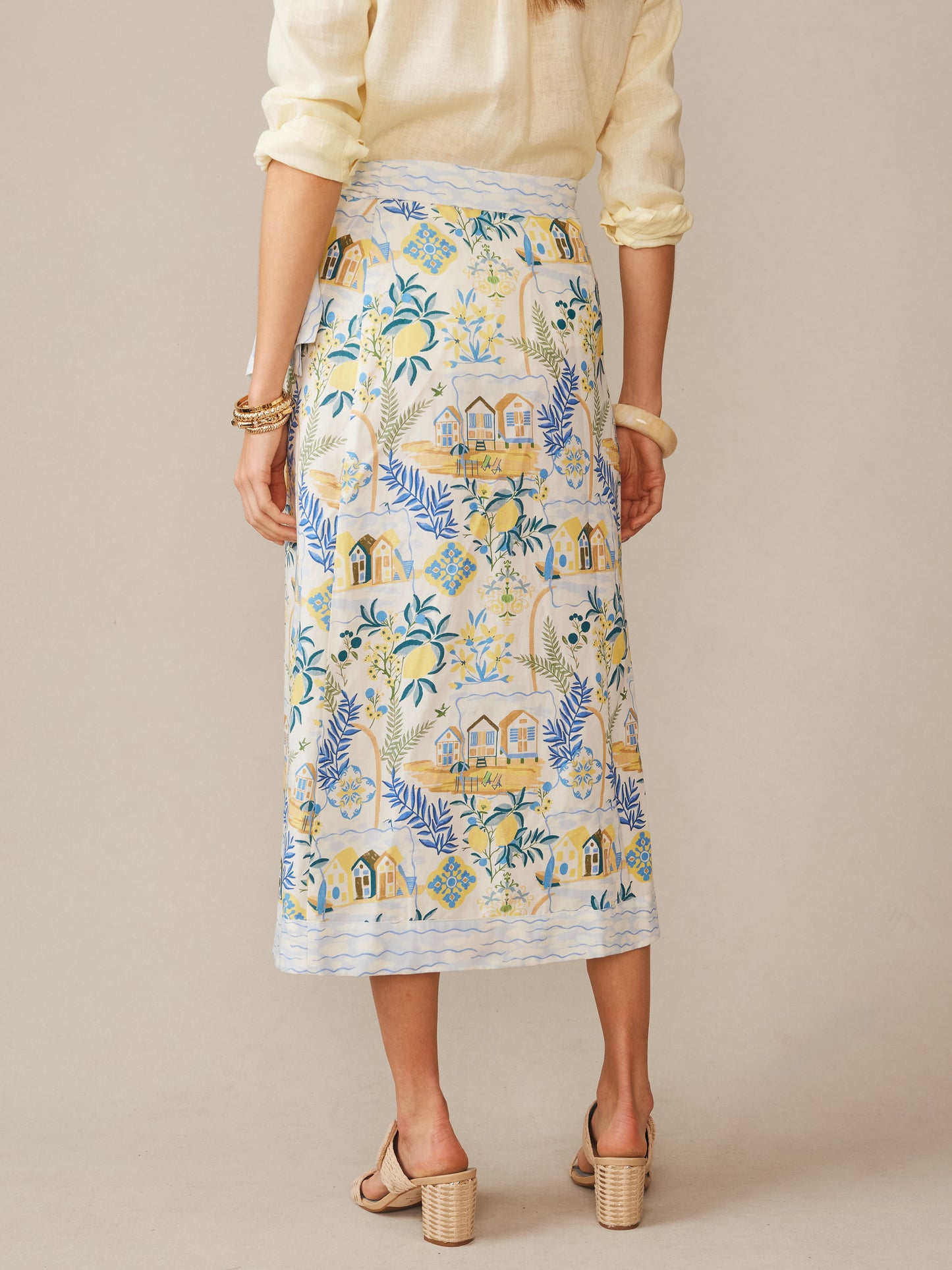 Woman wearing an effortlessly stylish Ardis Linen Blend Skirt in Amalfi Coast by J.McLaughlin, featuring a scenic coastal print in soft off-white, blue, and yellow hues, embodying enduring designs and innovative fabrics for a life well-lived.