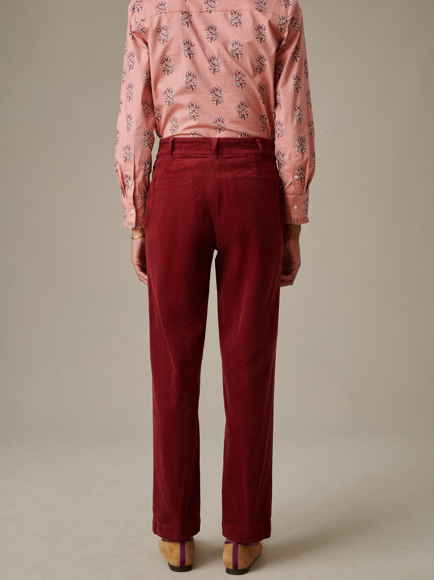 Back view of a person wearing deep red Avery Corduroy Pants by J.McLaughlin paired with a light pink floral patterned blouse, showcasing a stylish and timeless look.