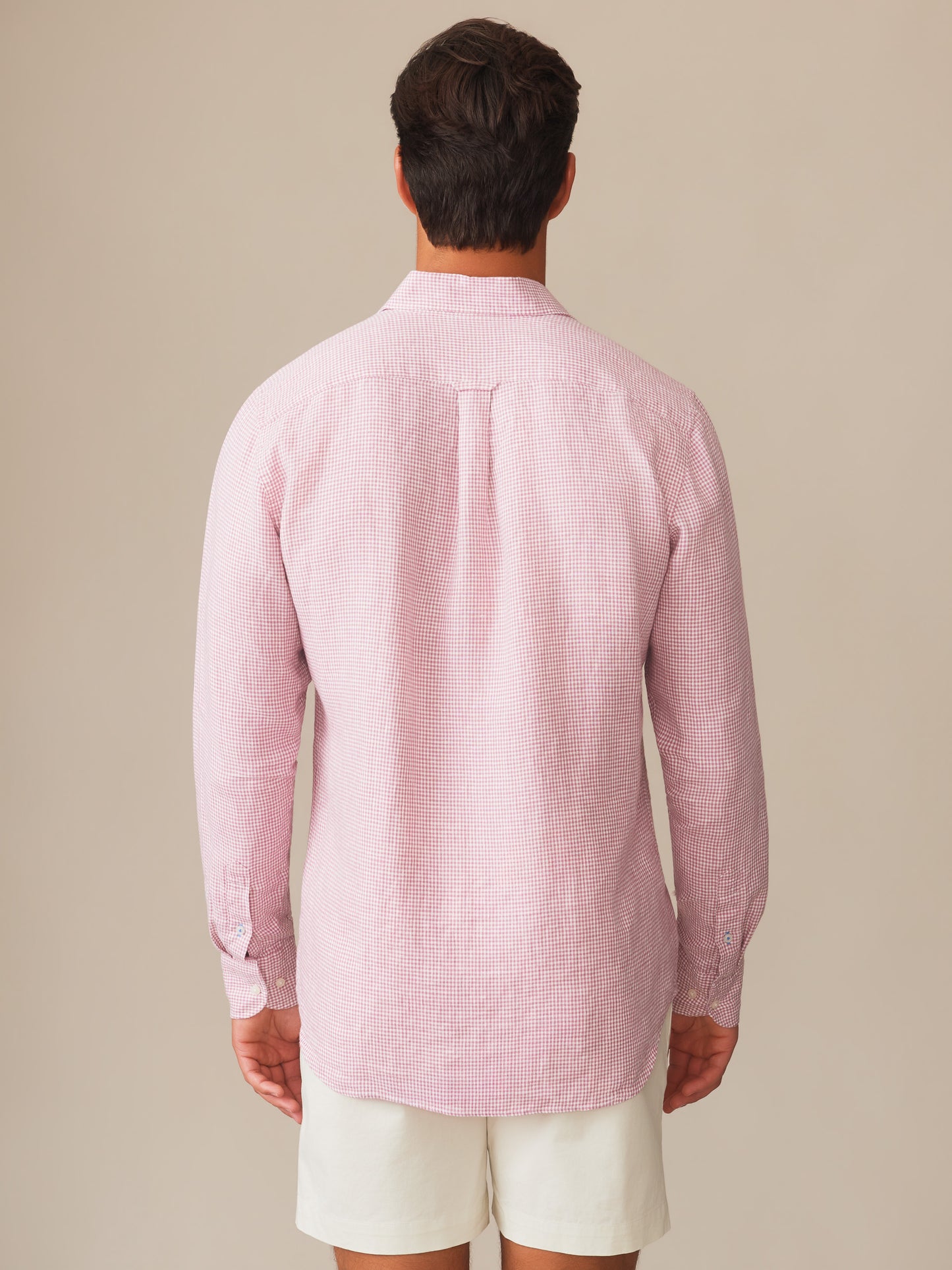 Back view of a man wearing a Gramercy Linen Shirt in Micro Gingham by J.McLaughlin, featuring a pink and white gingham pattern crafted with innovative fabrics for enduring designs and timeless style.
