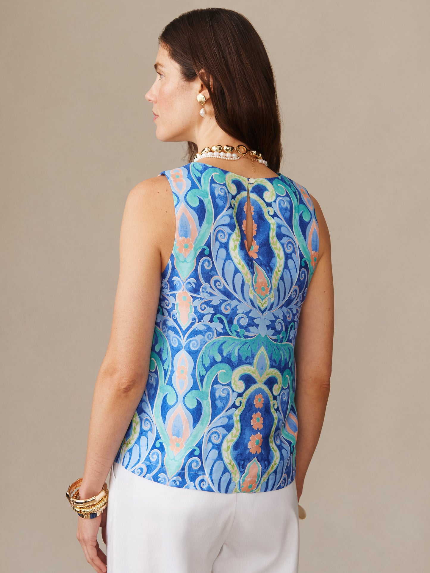 A woman wearing the Norie Silk Blend Blouse in Mini Deco Bloom by J.McLaughlin, featuring an effortlessly stylish pattern in blue and aqua tones, exemplifying enduring designs and innovative fabrics.