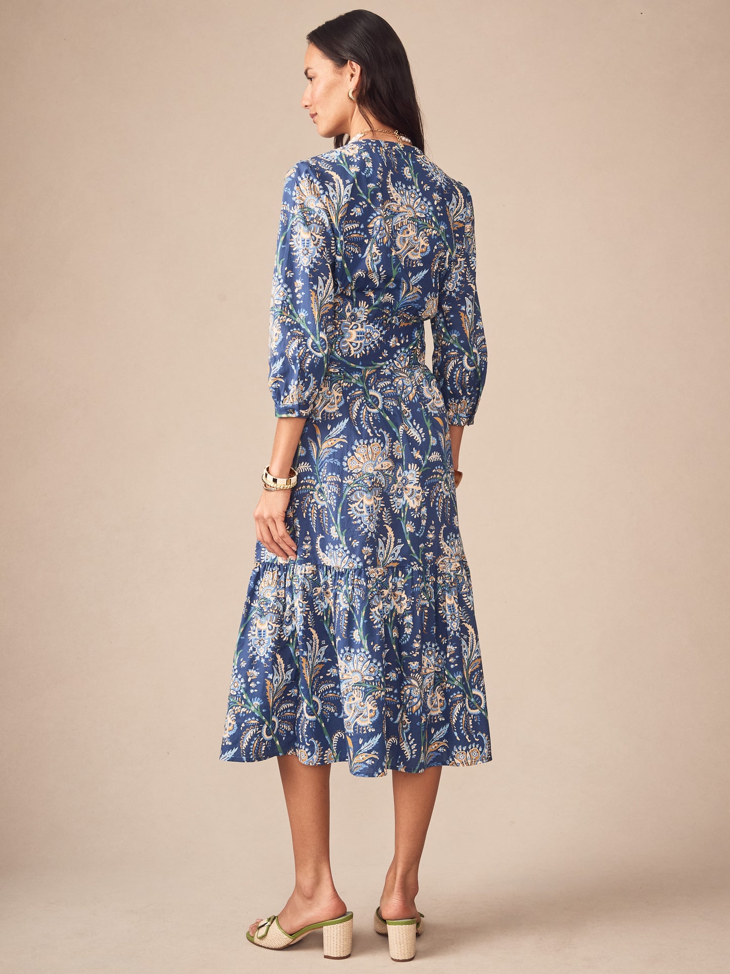A woman wearing the Cerina Dress in Maxi Heirloom Paisley by J.McLaughlin, featuring an elegant blue paisley pattern with three-quarter sleeves, embodying effortlessly stylish, enduring designs and a legacy of timeless fashion. A destination for defining style. Life, Well-Lived.