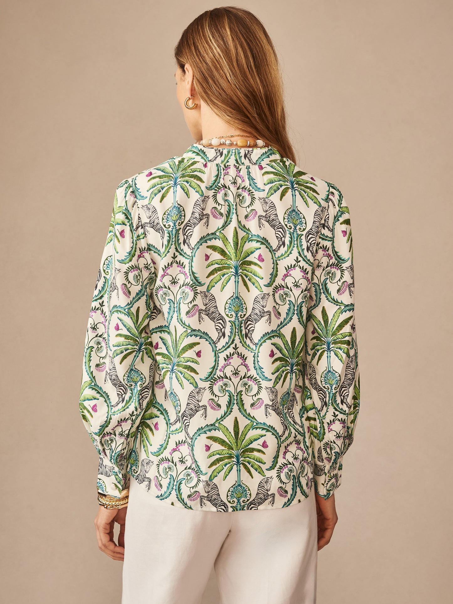 Woman wearing a Clover Silk Blend Blouse in Zebra Isle by J.McLaughlin featuring an intricate green palm and zebra pattern, showcasing effortlessly stylish, enduring designs with innovative fabrics.