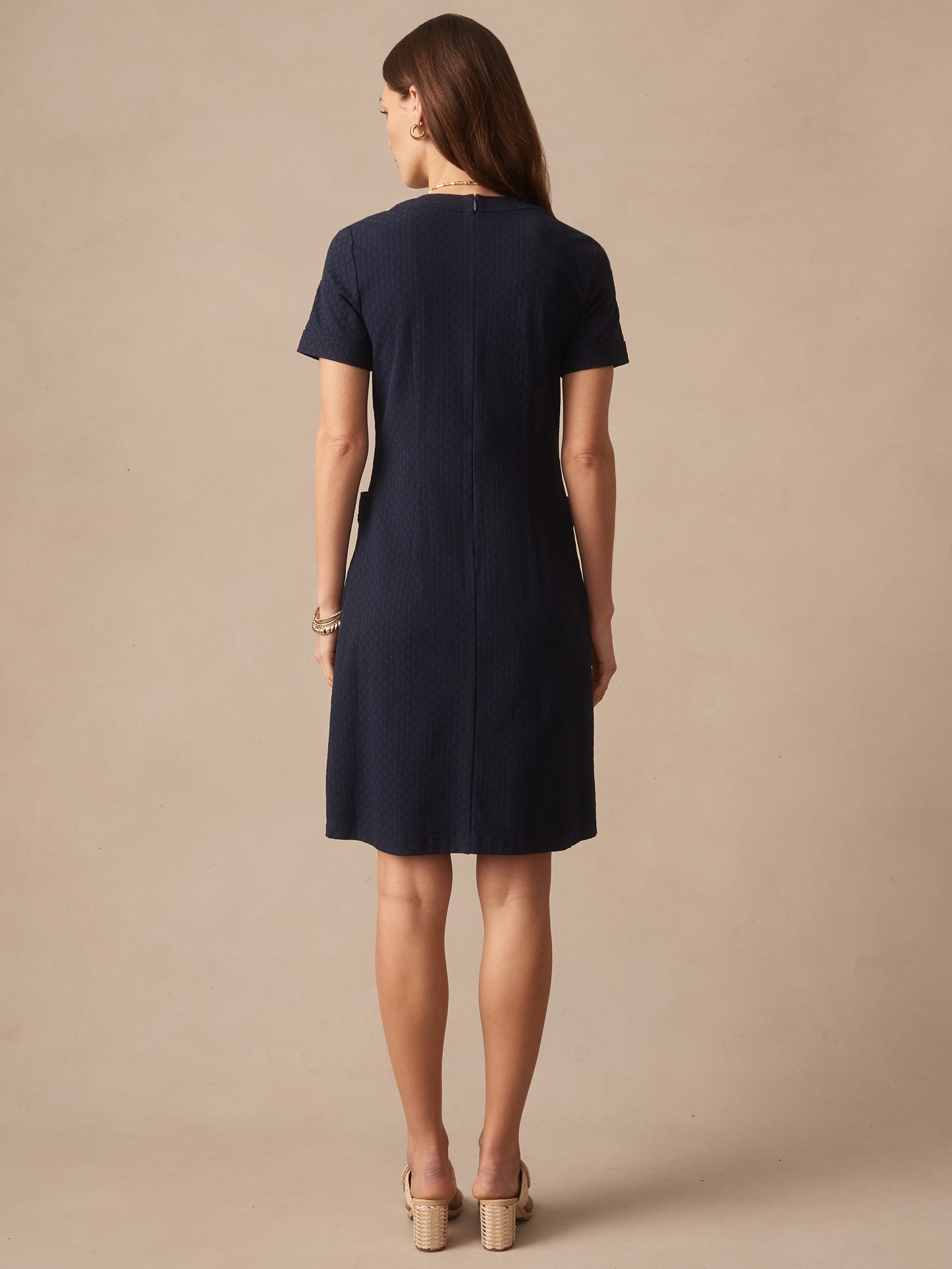 Woman wearing a navy Daphne Dress in Dashing Jacquard by J.McLaughlin, showcasing effortlessly stylish, enduring designs with innovative fabrics for a legacy of timeless fashion.