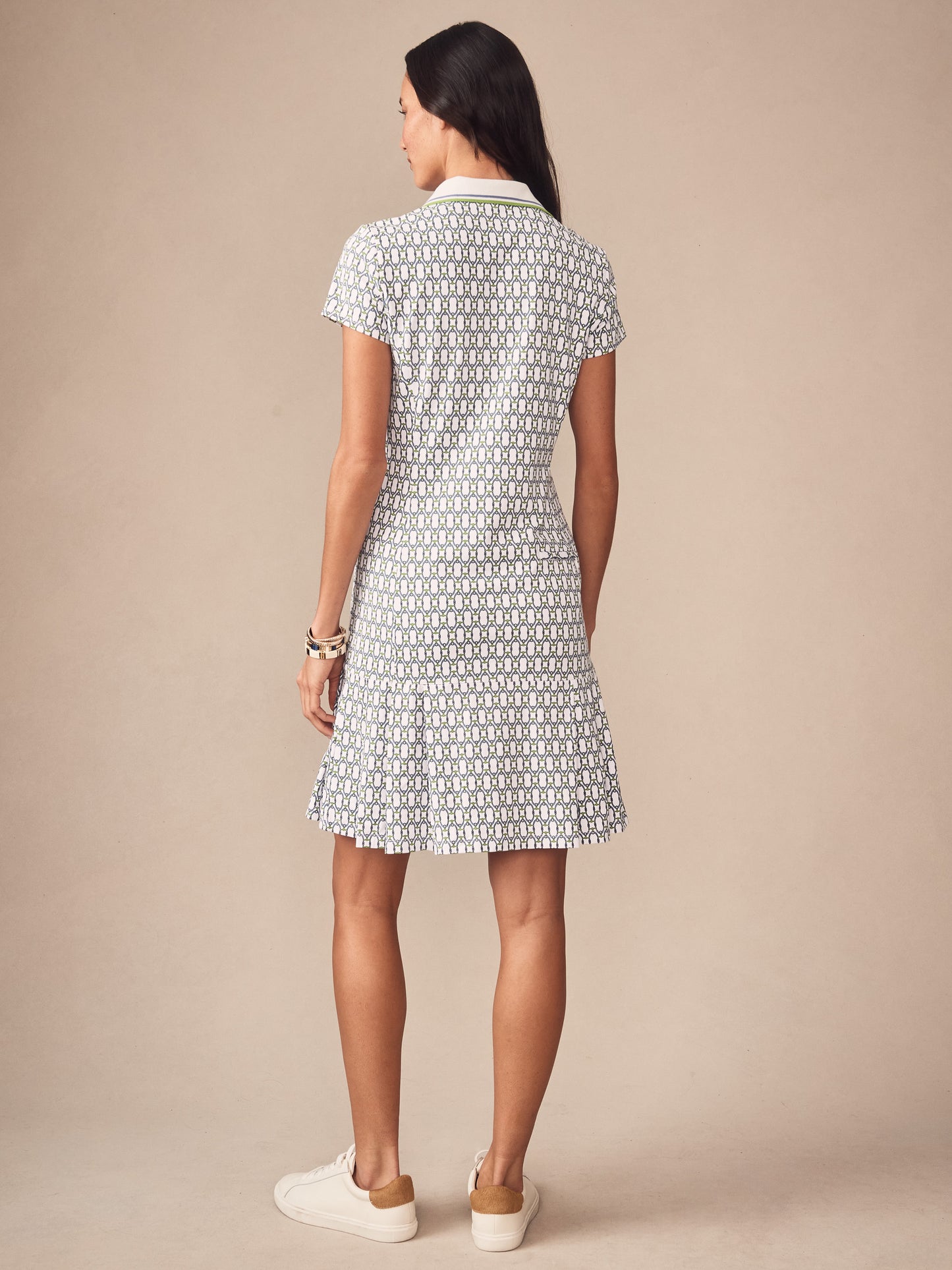Woman wearing the Dorte Dress in Signet Lock by J.McLaughlin, featuring a subtle patterned fabric in white, blue, and green tones, styled with white sneakers. Effortlessly stylish with enduring designs, reflecting innovative fabrics and a legacy of timeless fashion. A destination for defining style. Life, Well-Lived.