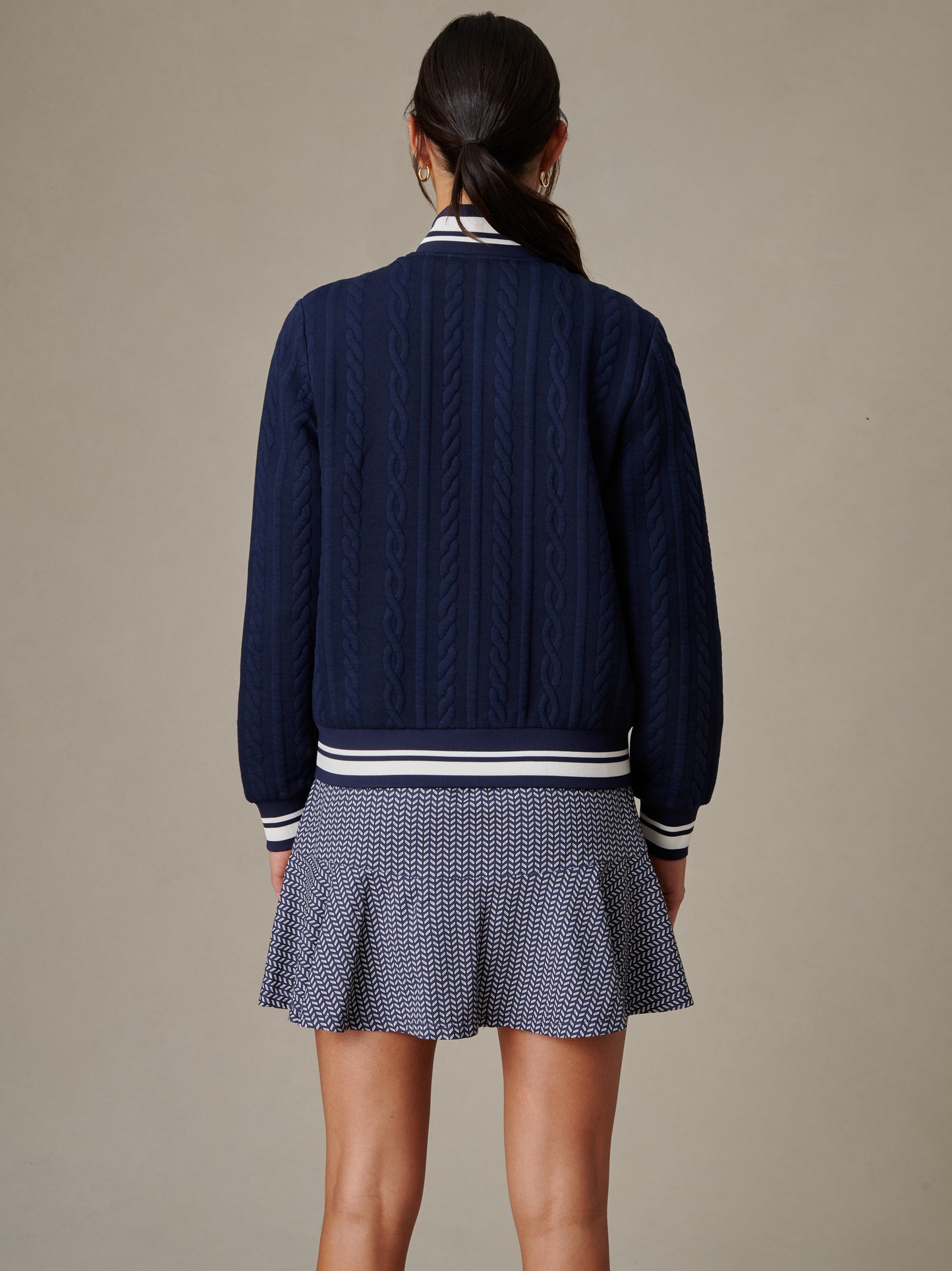 Woman wearing the Willa Jacket in Cable Jacquard by J.McLaughlin, showcasing innovative fabric and timeless design in a classic navy cable knit style.