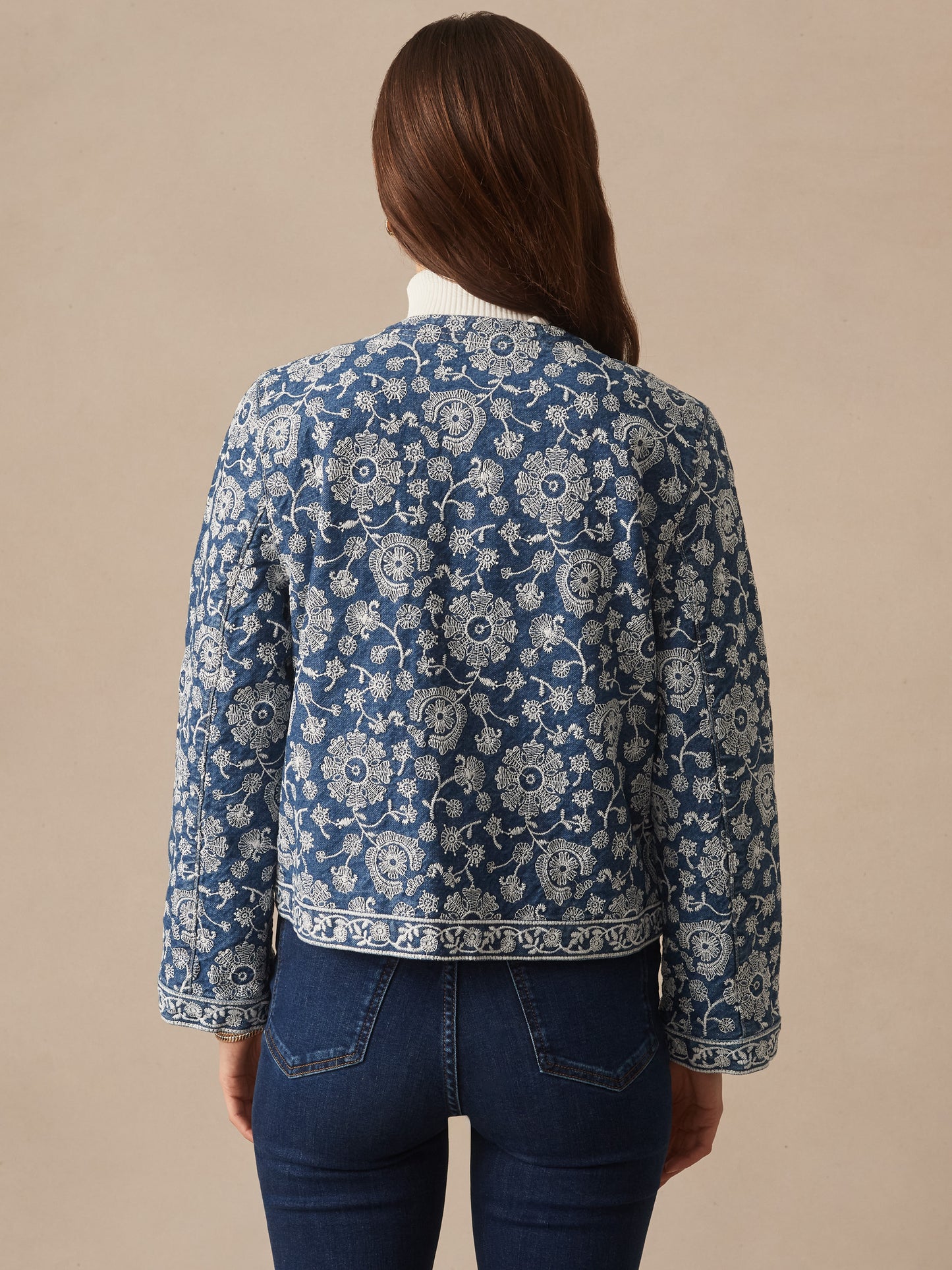 Woman seen from behind wearing the Isabel Jacket in Floral Daydream Embroidery by J.McLaughlin, featuring blue denim fabric with intricate white floral embroidery, effortlessly stylish and enduring designs reflecting a legacy of timeless fashion at a destination for defining style. Life, Well-Lived.