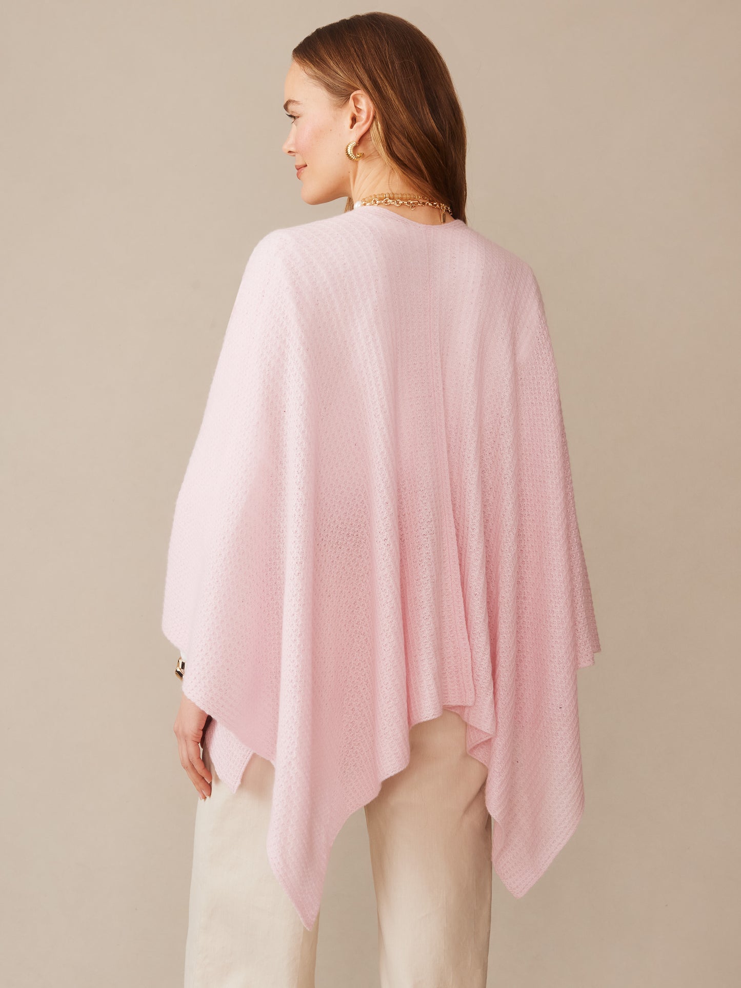 Woman wearing a soft pink Julianne Cashmere Wrap by J.McLaughlin, showcasing effortlessly stylish cashmere fabric with enduring designs for a legacy of timeless fashion.