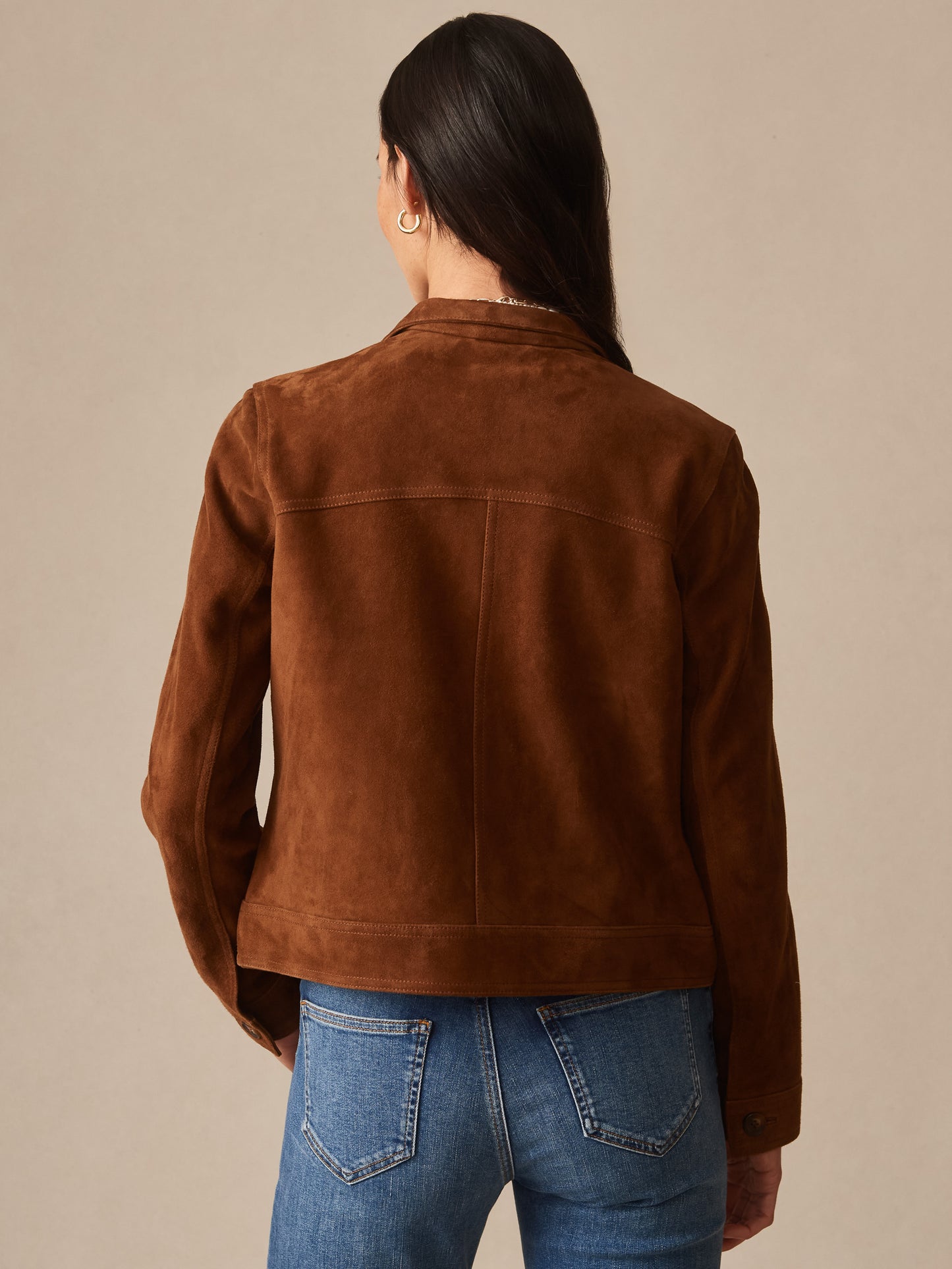 A woman wearing the Frances Suede Jacket by J.McLaughlin in rich brown, showcasing effortlessly stylish design and enduring craftsmanship, perfect for a life well-lived.