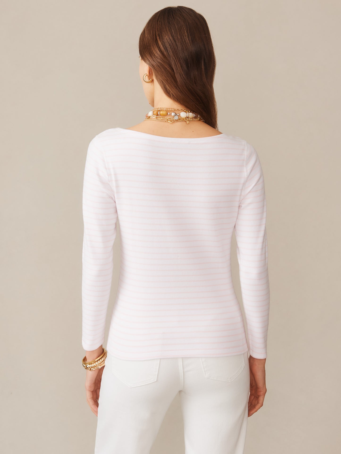 A woman wearing the Goldie Tee in Stripe by J.McLaughlin, styled with white pants and gold accessories, showcasing effortlessly stylish and enduring designs. A destination for defining style. Life, Well-Lived.