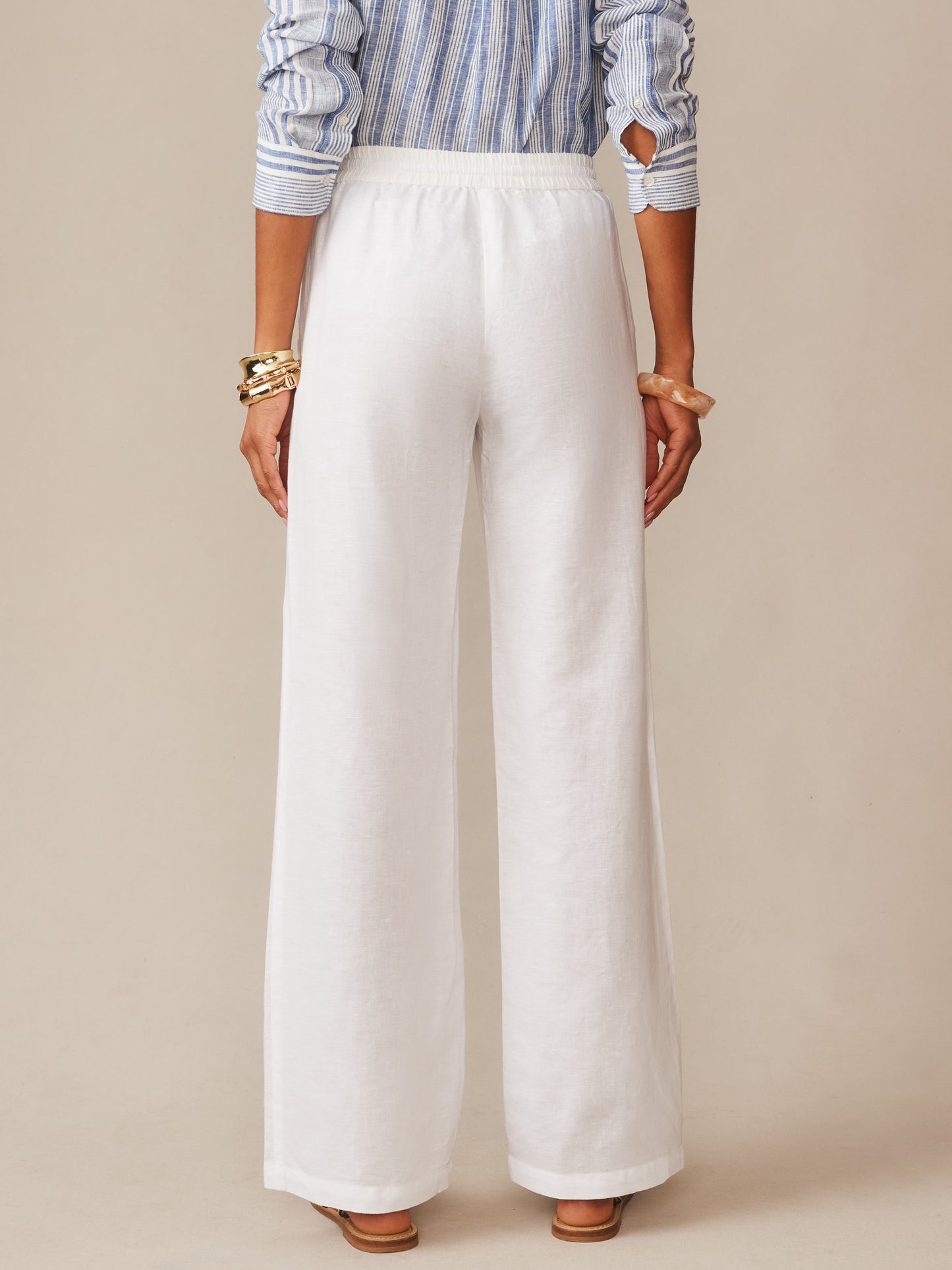 Back view of a model wearing white Irene Linen Pants by J.McLaughlin, featuring a relaxed fit and elastic waistband, embodying effortlessly stylish, enduring designs with innovative fabrics in a legacy of timeless fashion. A destination for defining style. Life, Well-Lived.