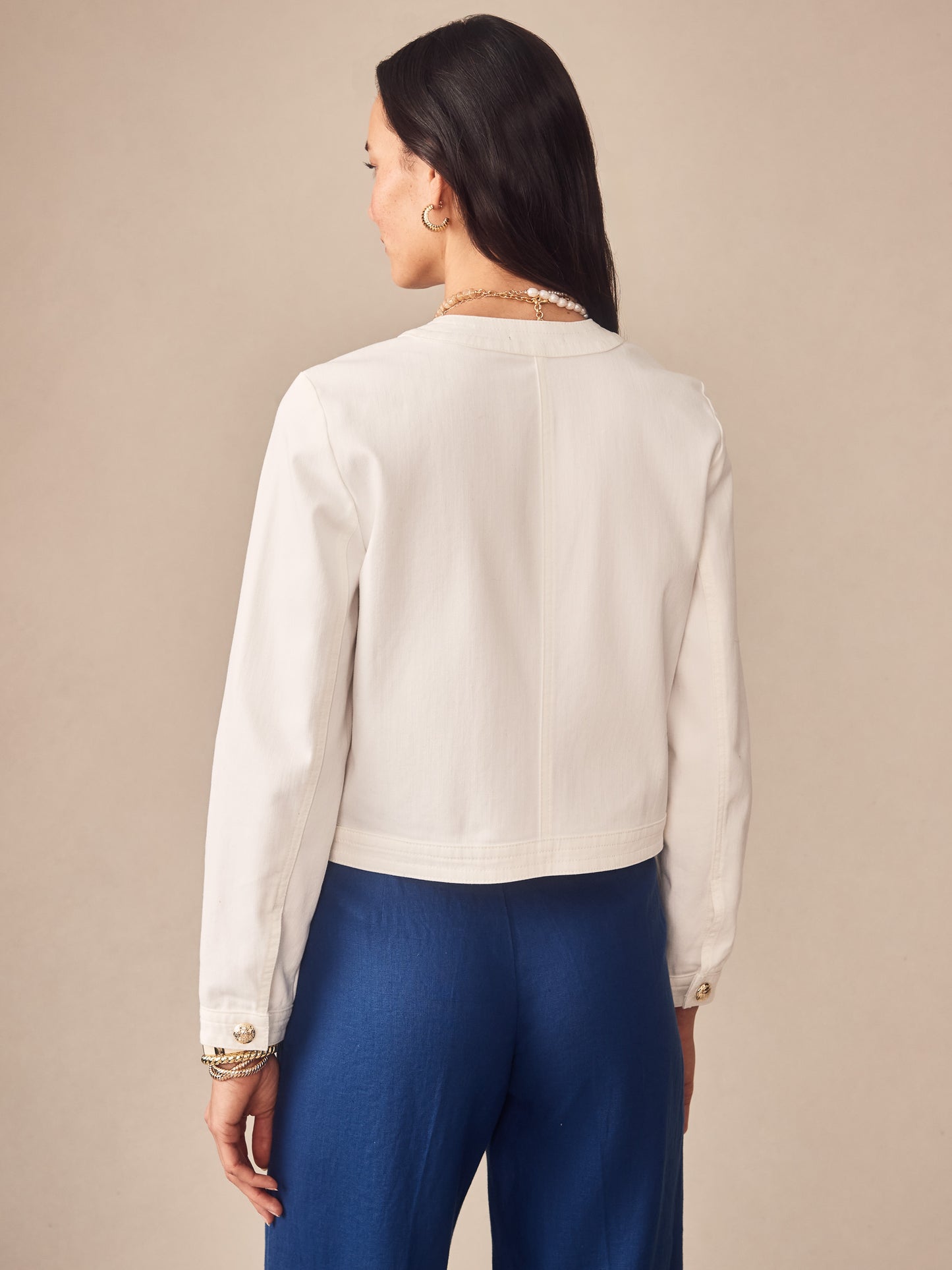 Woman wearing a white Jackie Denim Jacket by J.McLaughlin, showcasing effortlessly stylish design and enduring craftsmanship, embodying a legacy of timeless fashion.