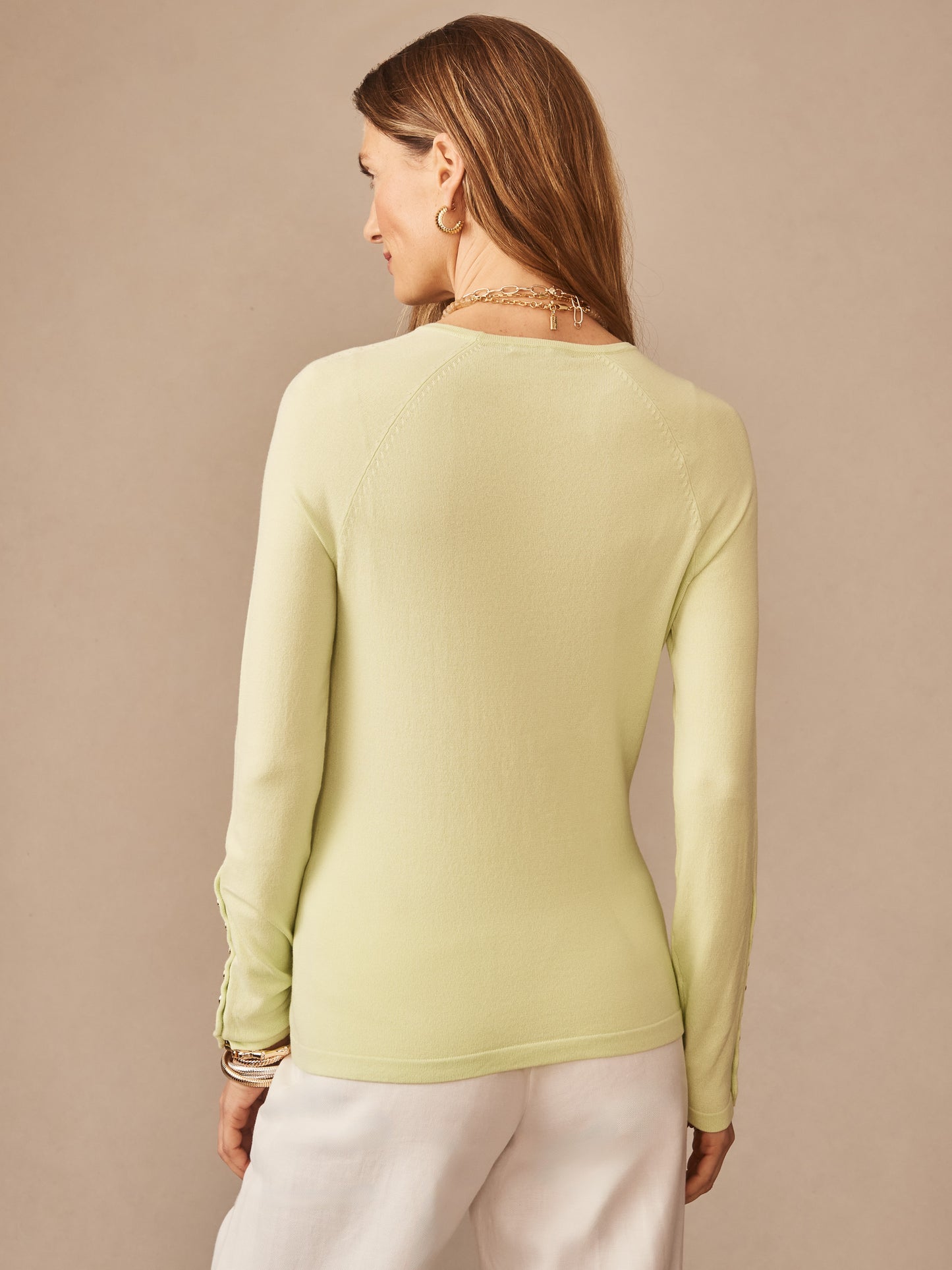 A woman wearing a lime green Jamey Sweater by J.McLaughlin, showcasing effortlessly stylish, enduring designs crafted with innovative fabrics for a legacy of timeless fashion.