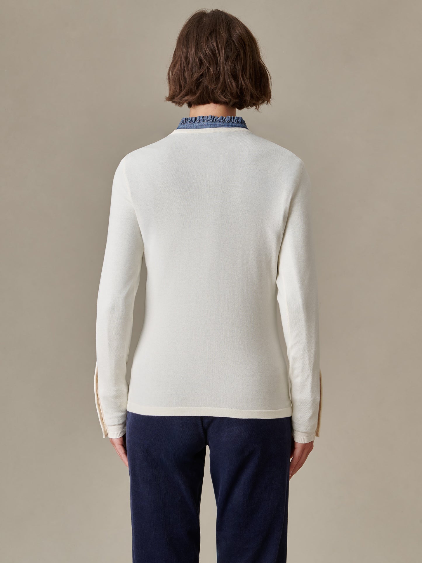 Back view of a person wearing a white Jamey Sweater by J.McLaughlin paired with navy pants, showcasing the timeless, effortlessly stylish design and quality craftsmanship.