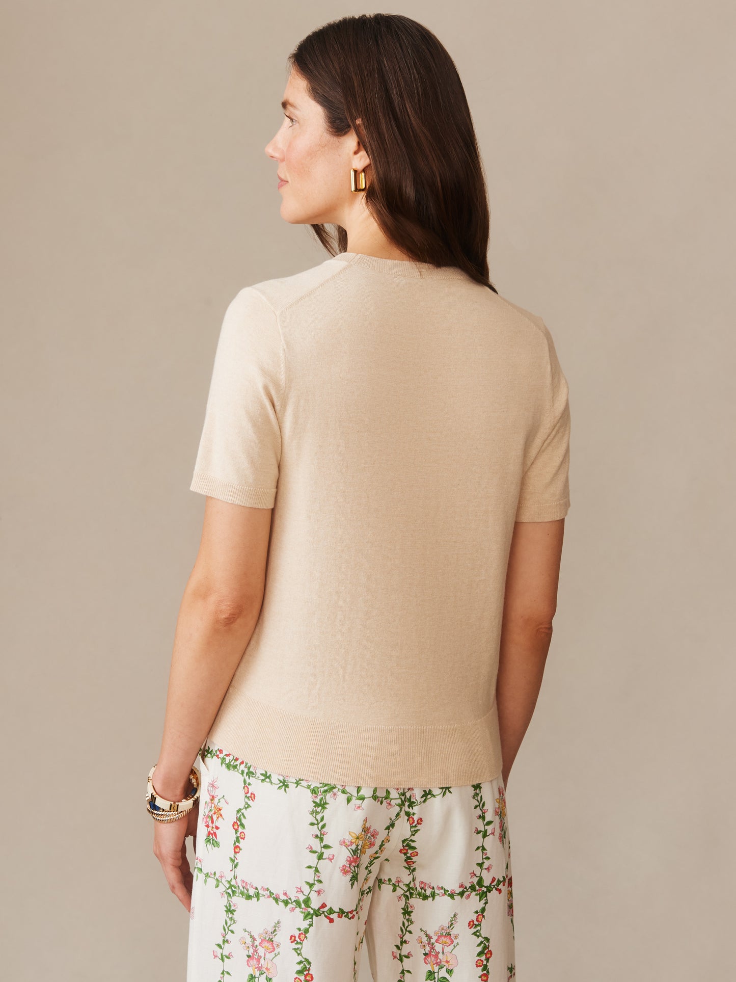 Woman shown from behind wearing a light oatmeal Joelle Sweater by J.McLaughlin paired with floral patterned pants, showcasing effortlessly stylish, enduring designs in innovative fabrics.