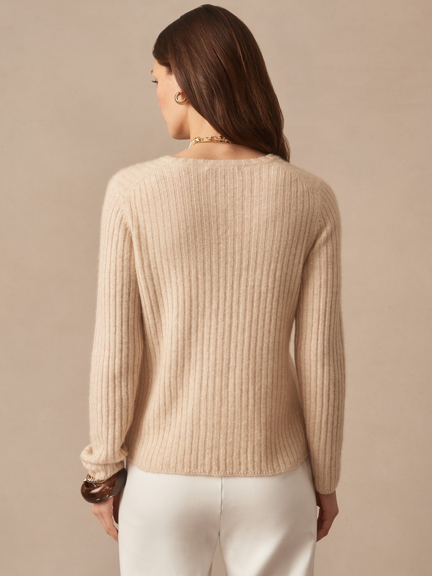 Back view of a woman wearing a soft oatmeal-colored Josephine Sweater by J.McLaughlin, showcasing effortlessly stylish ribbed knit fabric and enduring design for timeless fashion.