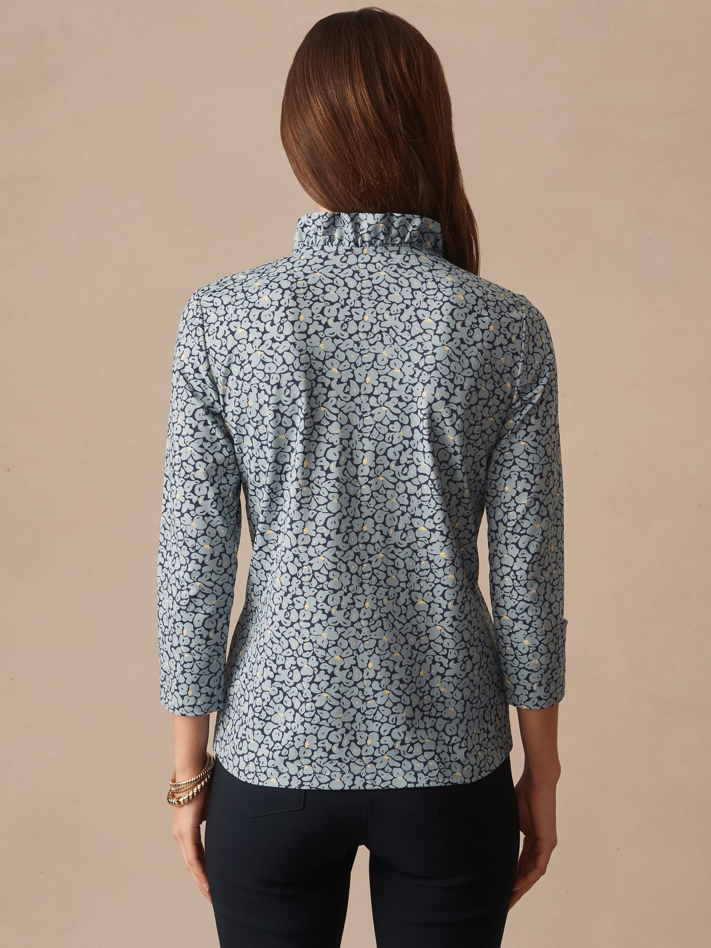 Woman wearing the Kate Ruffle Top in Celandine by J.McLaughlin, featuring a delicate floral pattern and ruffled collar, showcasing effortlessly stylish, enduring designs.