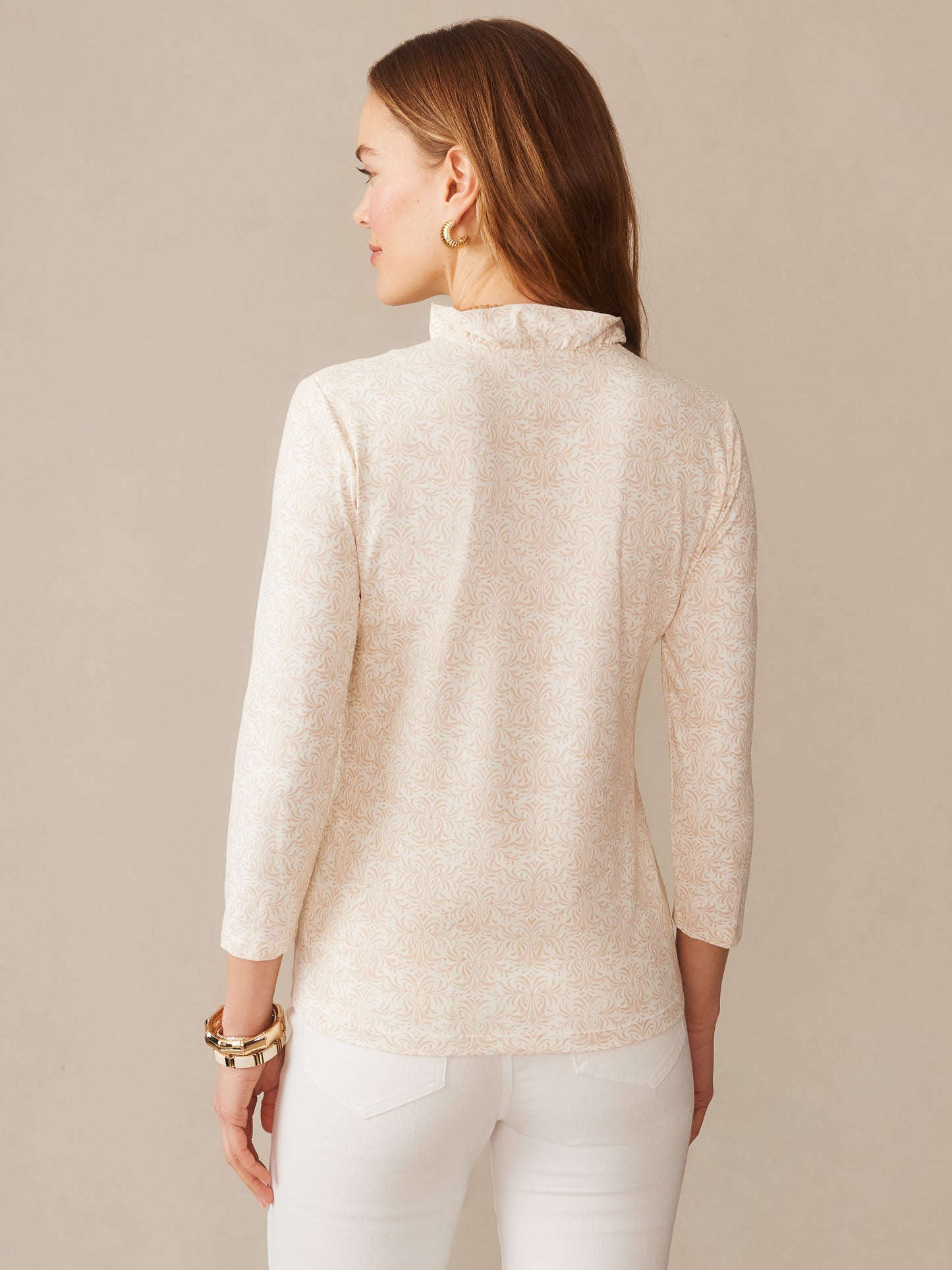 Woman wearing a Kate Ruffle Top in Mini Drawing Room by J.McLaughlin, featuring a subtle off-white and tan pattern with long sleeves, showcasing effortlessly stylish and enduring designs.