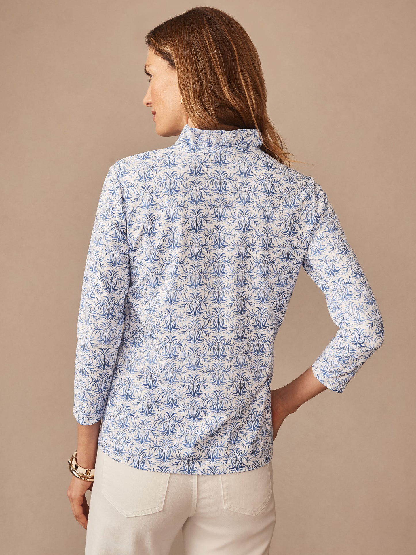 Woman wearing a stylish Kate Ruffle Top in Mini Drawing Room by J.McLaughlin, featuring an intricate blue pattern on a classic white fabric, embodying effortlessly stylish, enduring designs in a top. A destination for defining style. Life, Well-Lived.