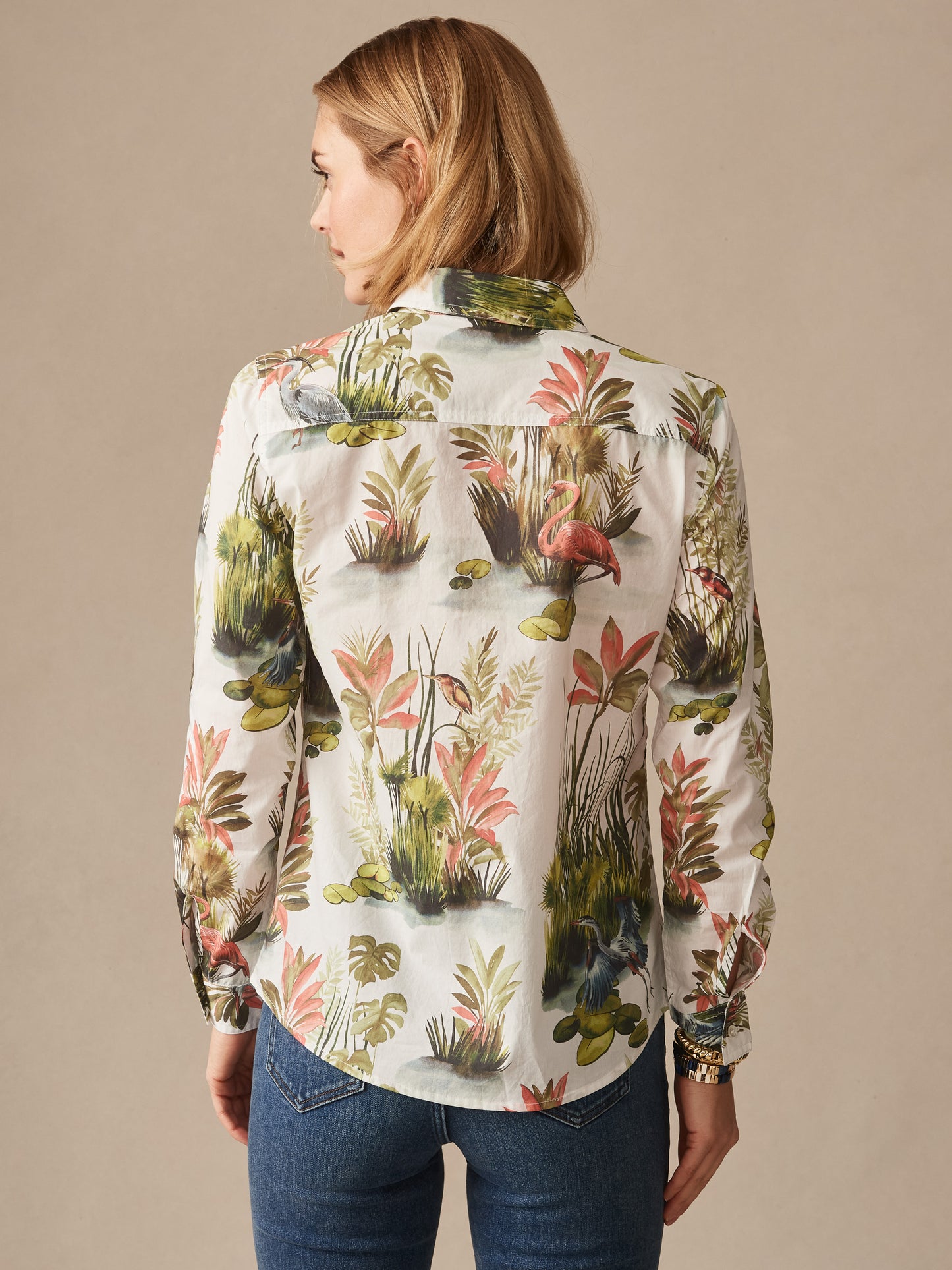 Woman wearing the Lois Shirt in Tidal Palms by J.McLaughlin, featuring a vibrant tropical print of flamingos and lush greenery, showcasing effortlessly stylish, enduring designs in a classic blouse.