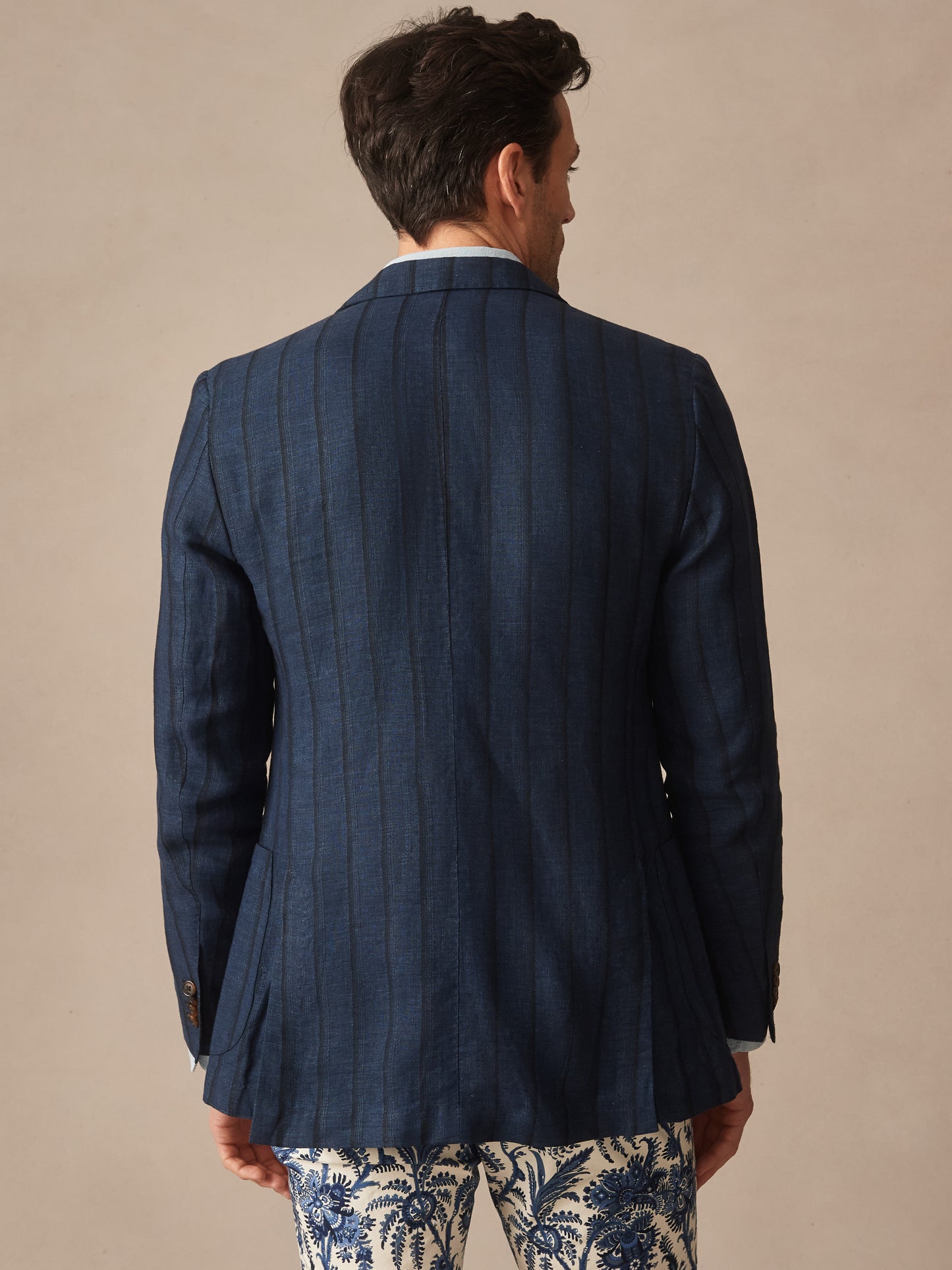 Man seen from behind wearing the Brera Linen Silk Sport Coat in Stripe by J.McLaughlin, paired with patterned pants, showcasing effortlessly stylish craftsmanship and enduring designs in innovative fabrics.