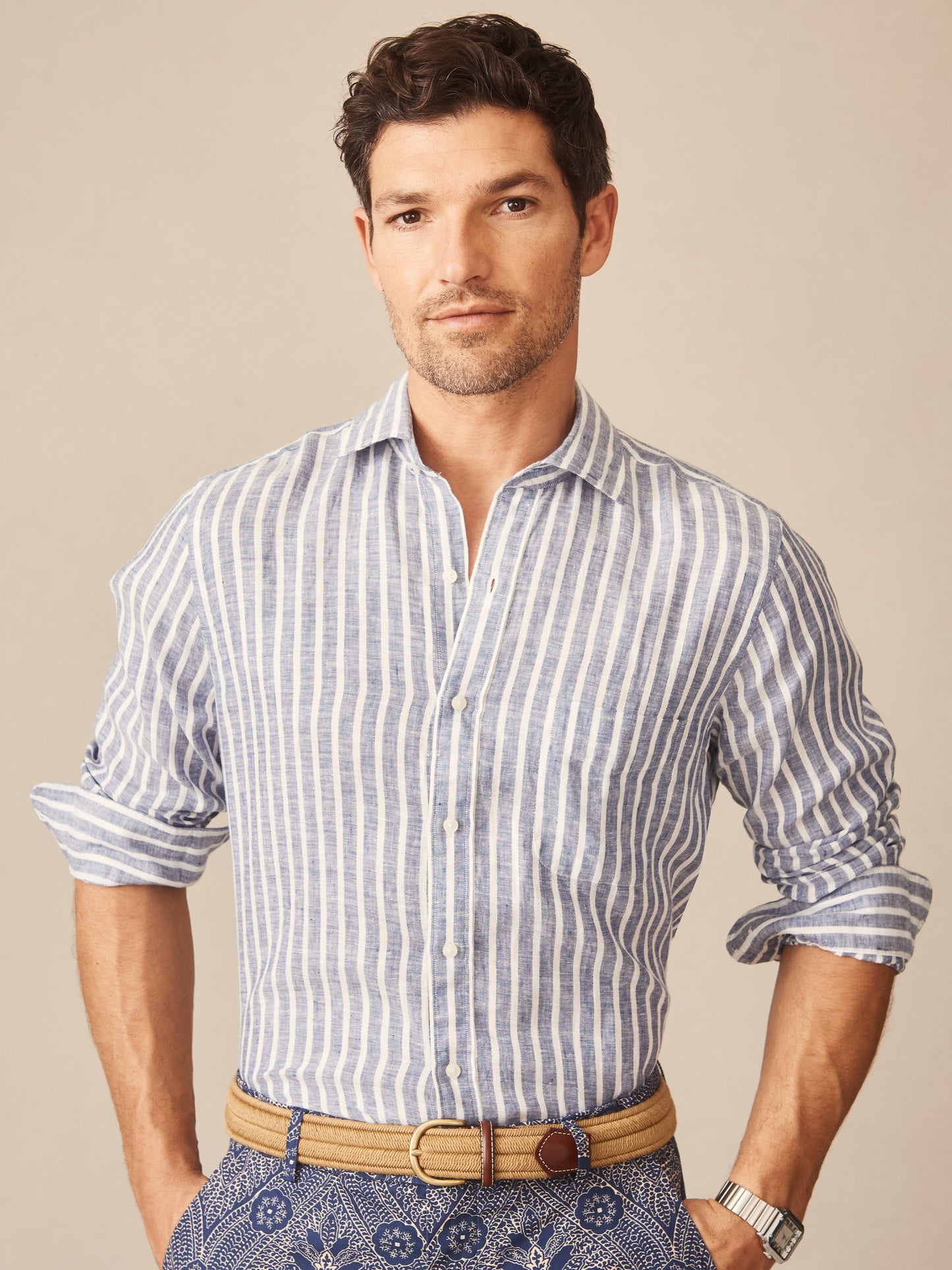 Man wearing a Gramercy Linen Shirt in Dobby Stripe by J.McLaughlin, showcasing effortlessly stylish, enduring designs crafted with innovative fabrics, embodying a legacy of timeless fashion.