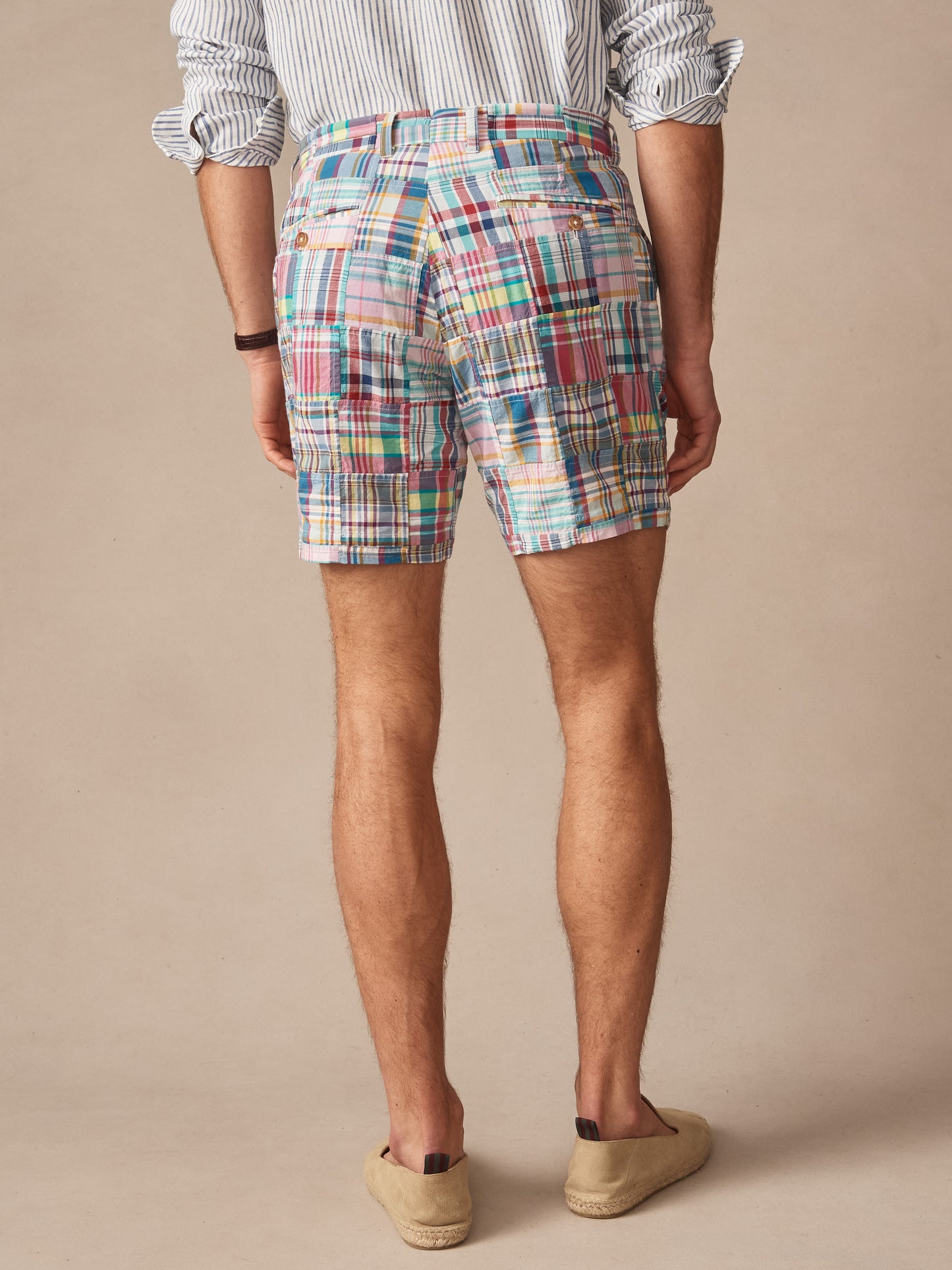 Man wearing J.McLaughlin Chatham Shorts in Patchwork, featuring a colorful patchwork pattern with multiple hues, paired with a striped shirt and casual slip-on shoes, showcasing an effortlessly stylish look with enduring designs and innovative fabrics, embodying a legacy of timeless fashion. A destination for defining style. Life, Well-Lived.