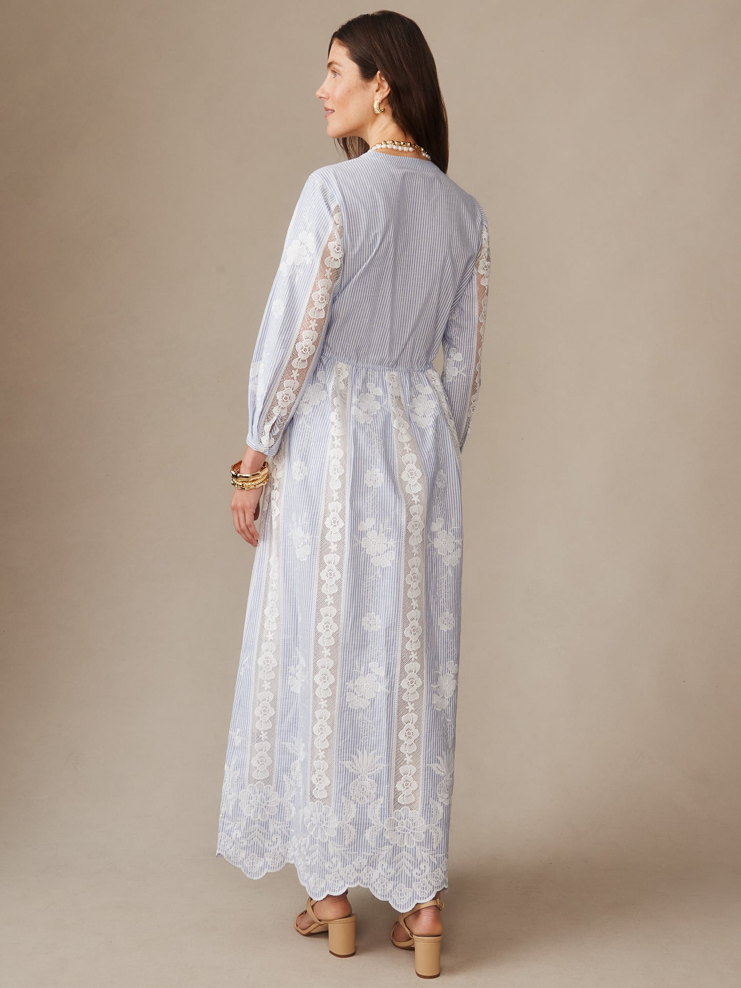 A woman wearing the Margaret Dress in Stripe by J.McLaughlin, featuring a delicate blue and white striped pattern with intricate lace detailing on the sleeves and skirt, showcasing effortlessly stylish, enduring designs with a legacy of timeless fashion, a destination for defining style. Life, Well-Lived.