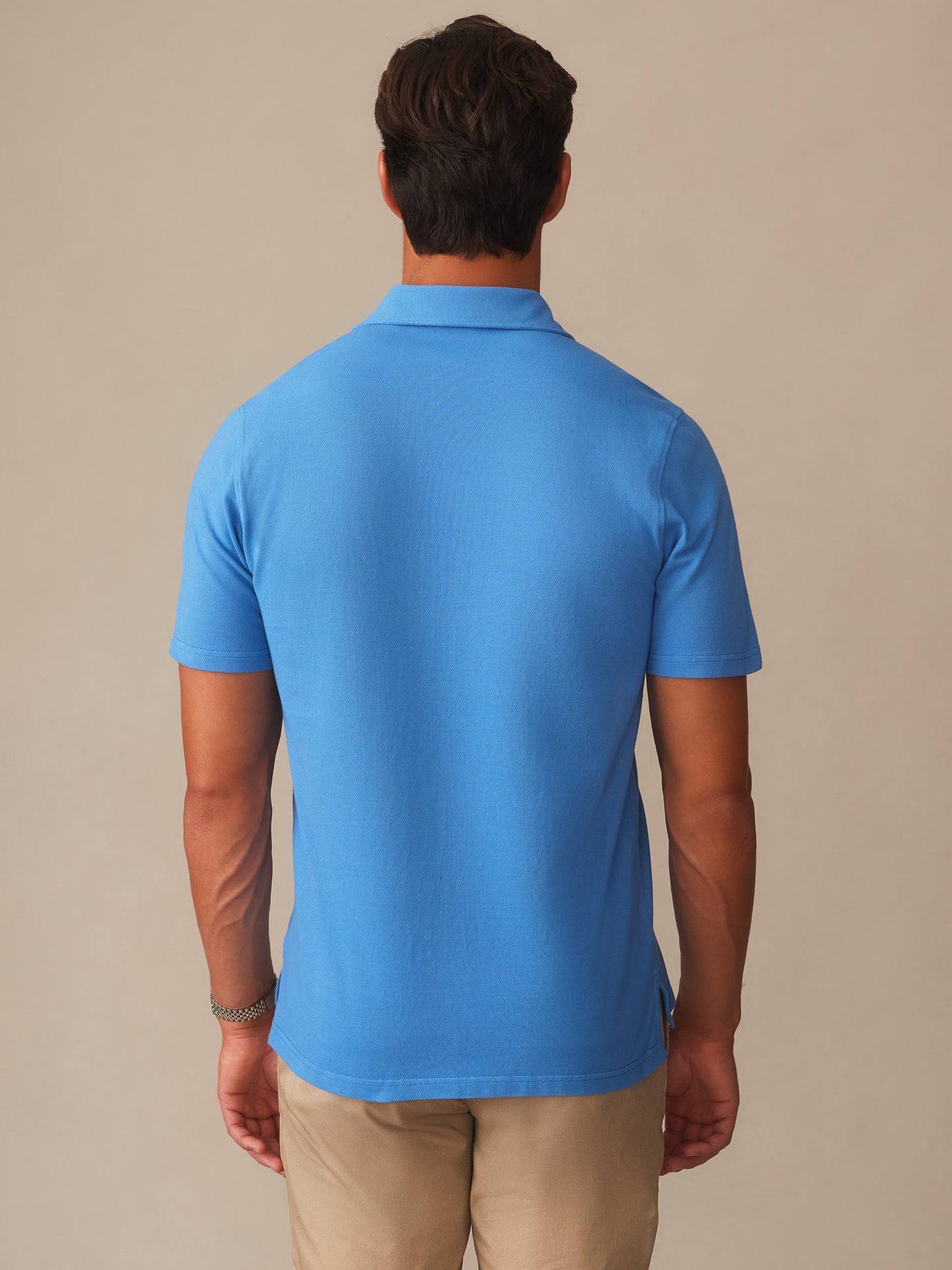 Man wearing a pacific blue Mantle Pique Polo by J.McLaughlin shown from the back, featuring effortlessly stylish, enduring designs crafted with innovative fabrics. A destination for defining style. Life, Well-Lived.
