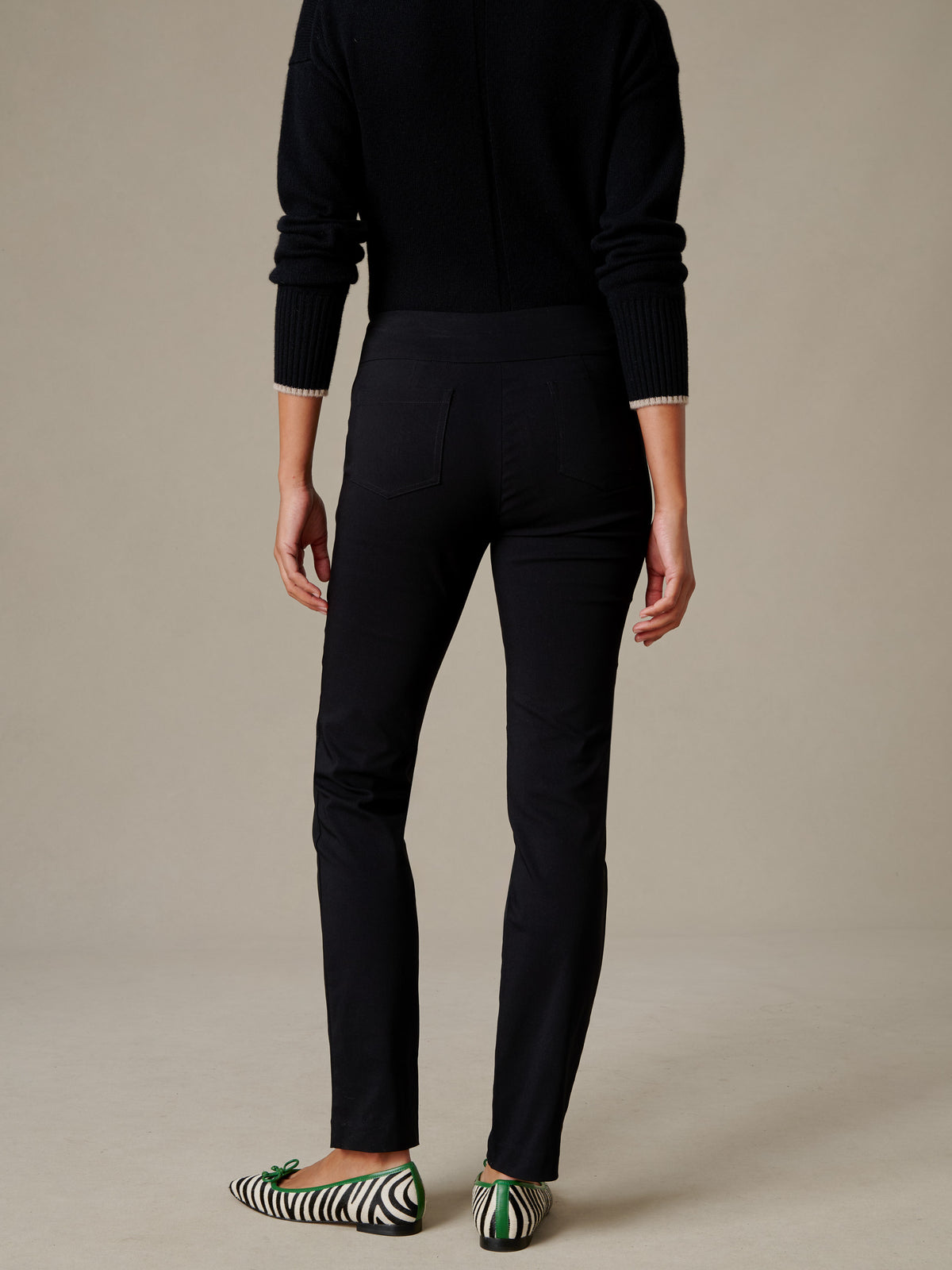 J.McLaughlin Masie Pants shown in a sleek black tailored stretch fit with slim legs and back pockets styled with a black sweater and patterned flats