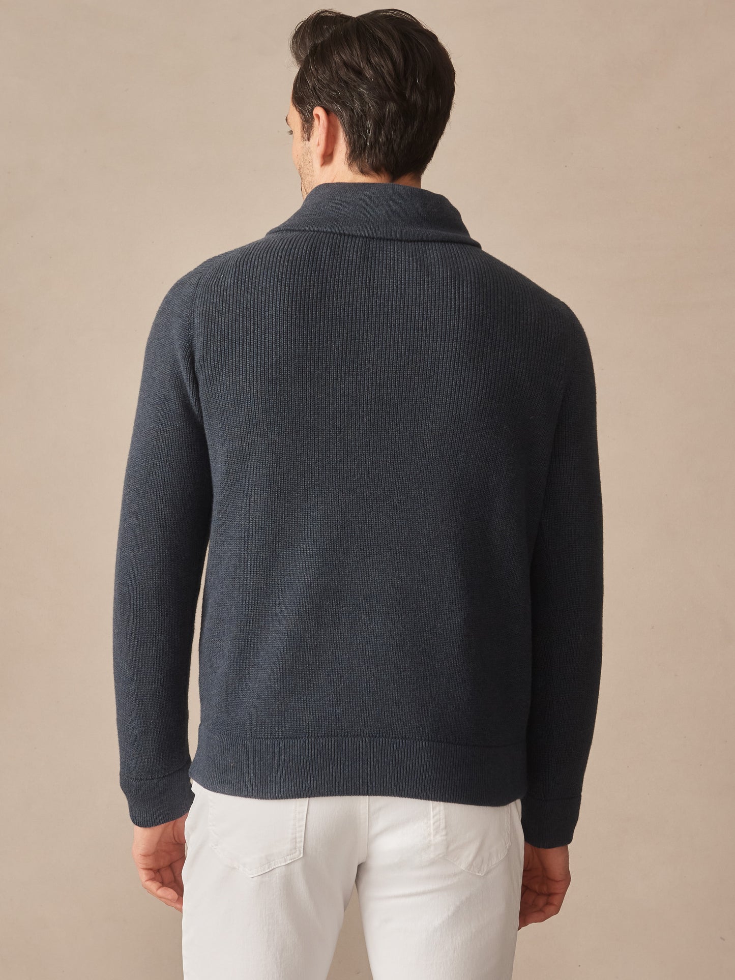 Man wearing a dark blue Hudson Sweater by J.McLaughlin, showcasing effortlessly stylish knitwear with enduring designs crafted from innovative fabrics, embodying a legacy of timeless fashion.