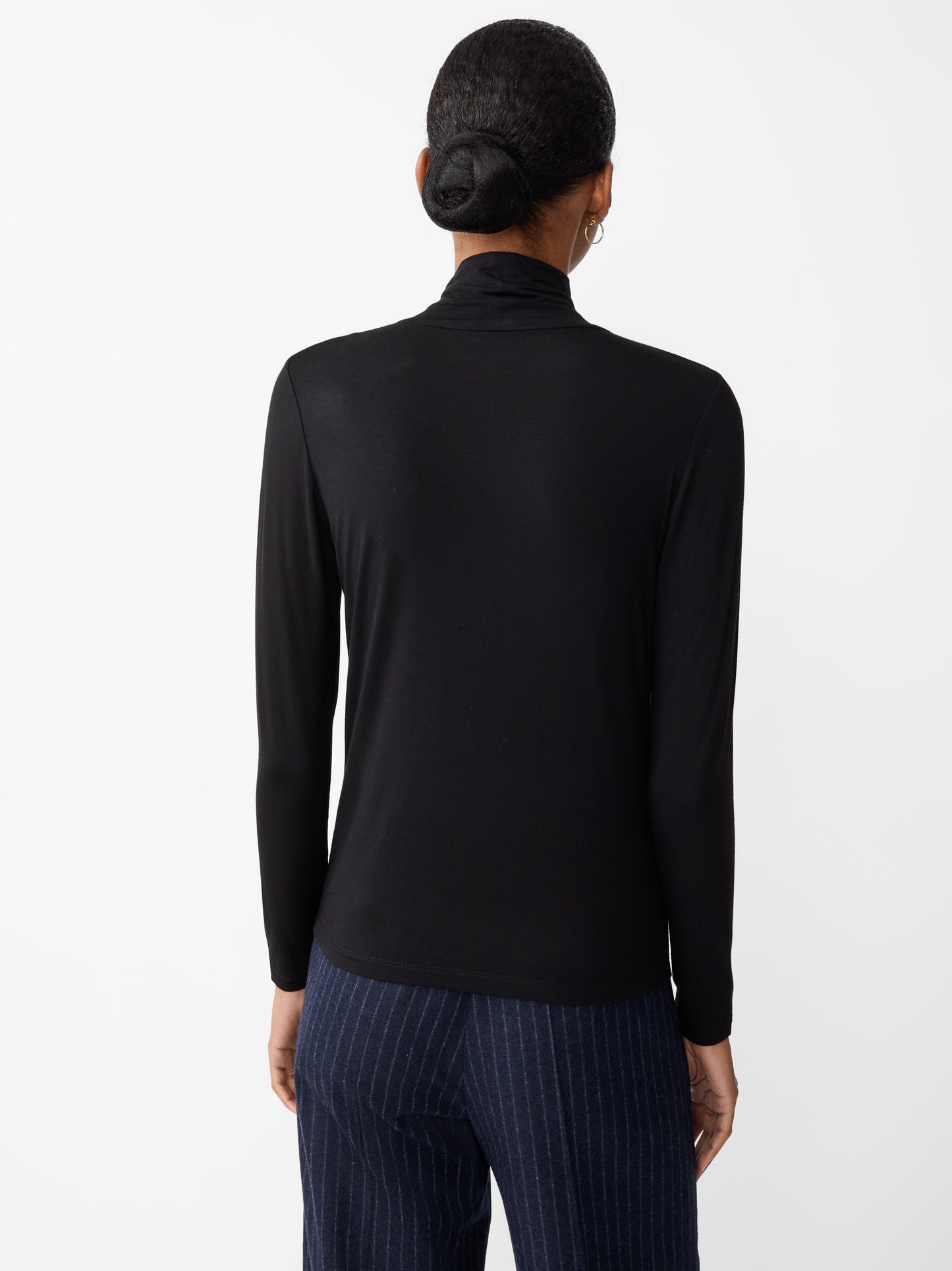 Model wearing J.McLaughlin Nadia turtleneck in black made with rayon/spandex.