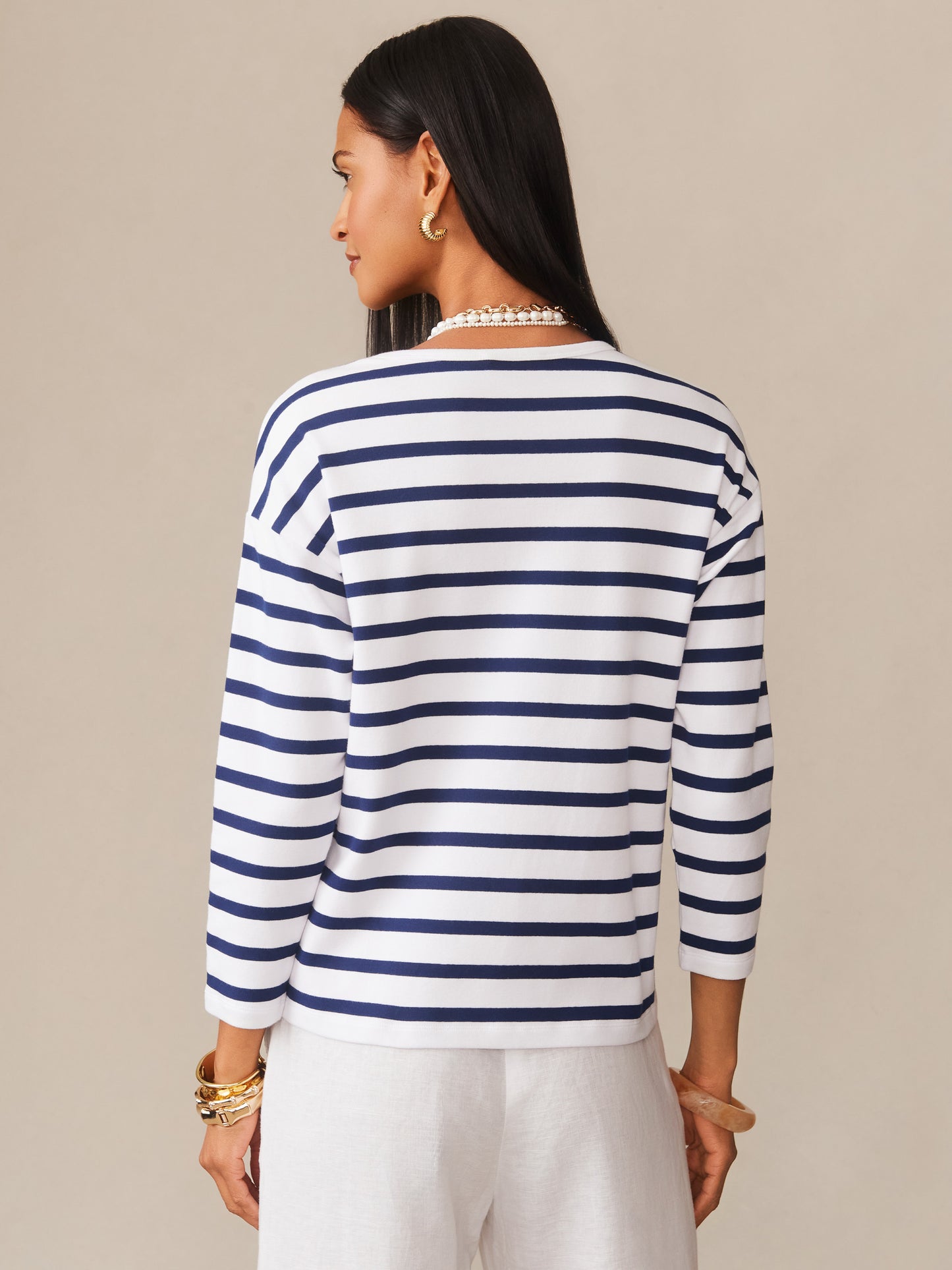 Woman modeling the Nico Tee in Stripe by J.McLaughlin, featuring navy and white horizontal stripes paired with white pants, showcasing effortlessly stylish, enduring designs. A destination for defining style. Life, Well-Lived.
