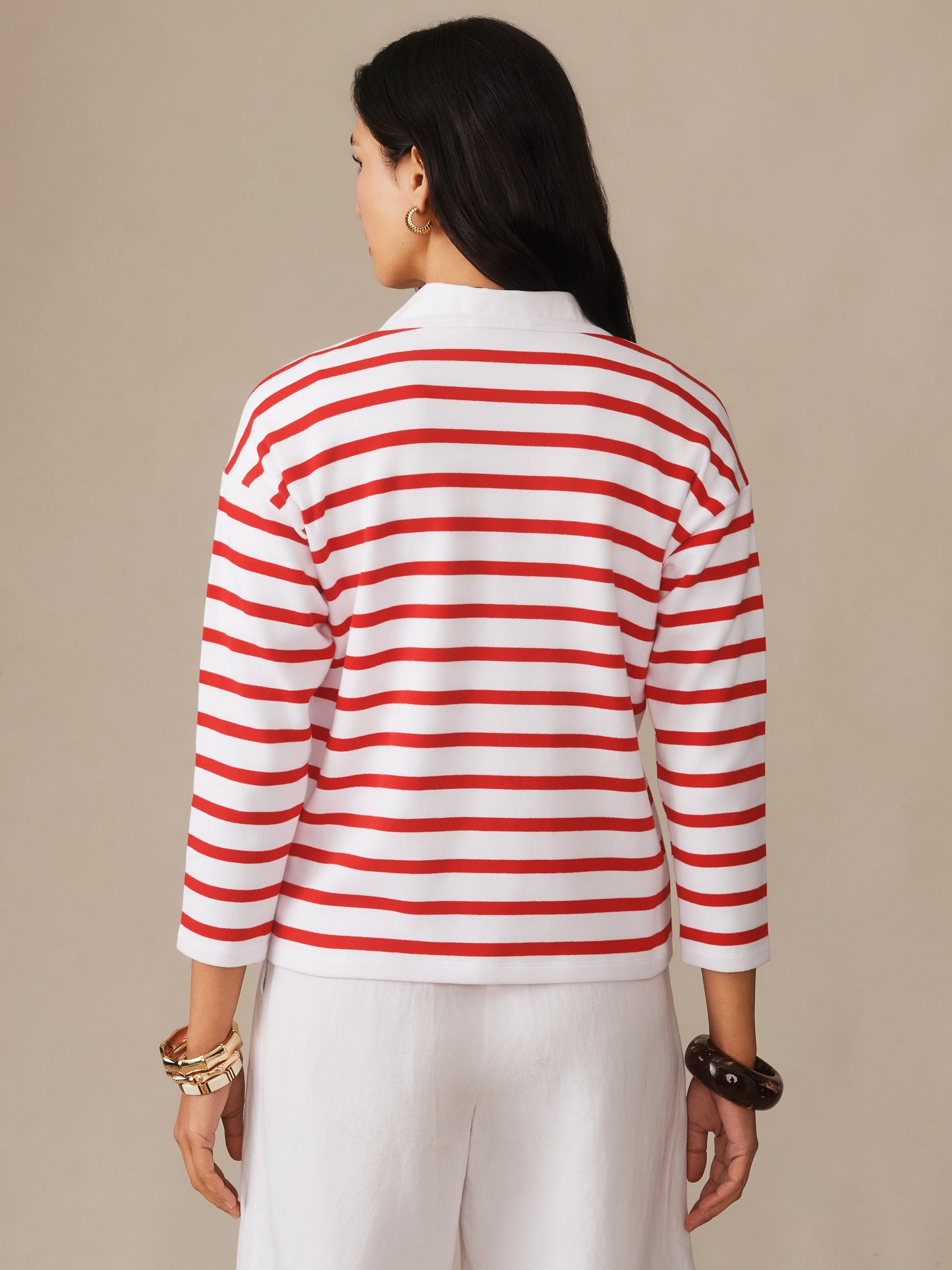 A woman seen from behind wearing the Nico Tee in Stripe featuring classic red horizontal stripes on white, paired with white pants, representing J.McLaughlin’s effortlessly stylish, enduring designs and legacy of timeless fashion.