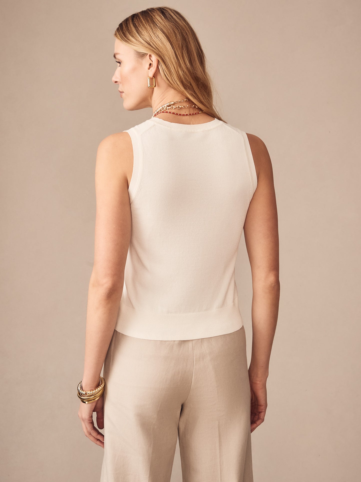 Woman wearing an ivory Opal Sweater Tank by J.McLaughlin, showcasing an effortlessly stylish sleeveless top with enduring designs and innovative fabrics, embodying a legacy of timeless fashion. A destination for defining style. Life, Well-Lived.