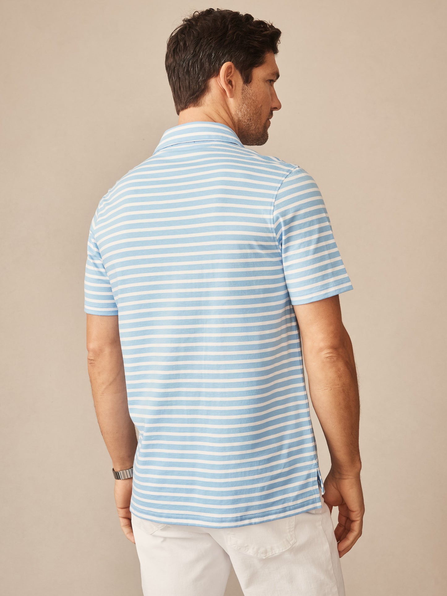 Man wearing Owens Polo in Breton Stripe by J.McLaughlin, showcasing effortlessly stylish and enduring design in a light blue and white striped shirt, part of a legacy of timeless fashion. A destination for defining style. Life, Well-Lived.