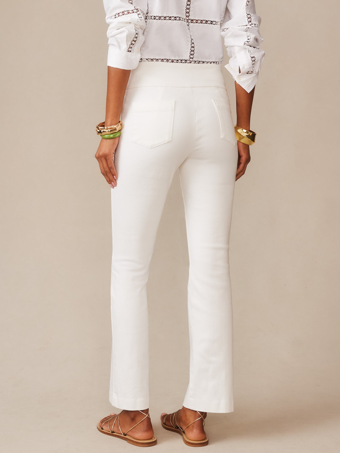Woman wearing white Rylie Jeans by J.McLaughlin, paired with a patterned white blouse and gold and green bangles, showcasing effortlessly stylish and enduring designs for timeless fashion.