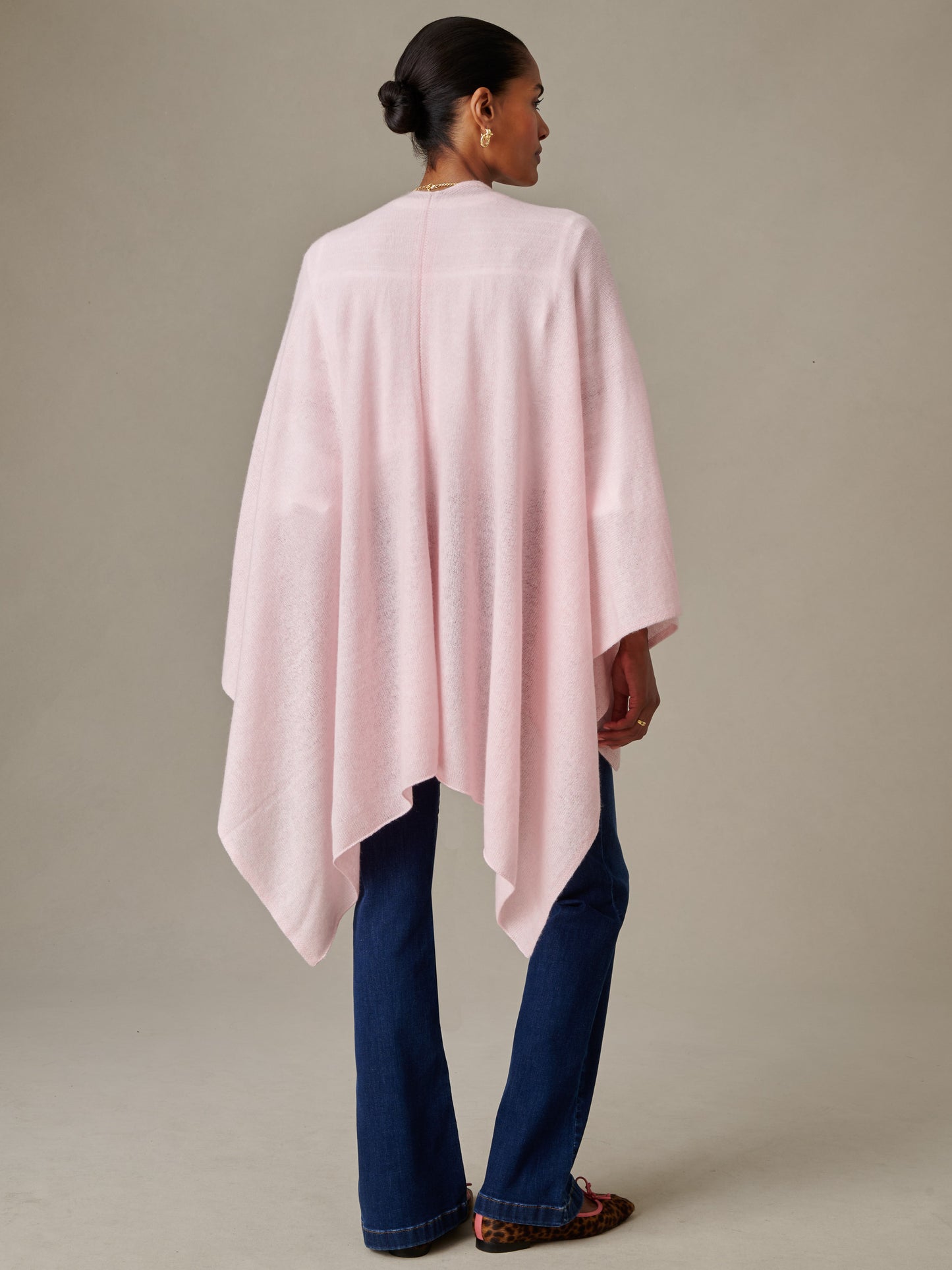 Woman wearing a soft pink Rossi Cashmere Wrap by J.McLaughlin over dark blue jeans and leopard print flats, embodying effortlessly stylish, enduring designs.