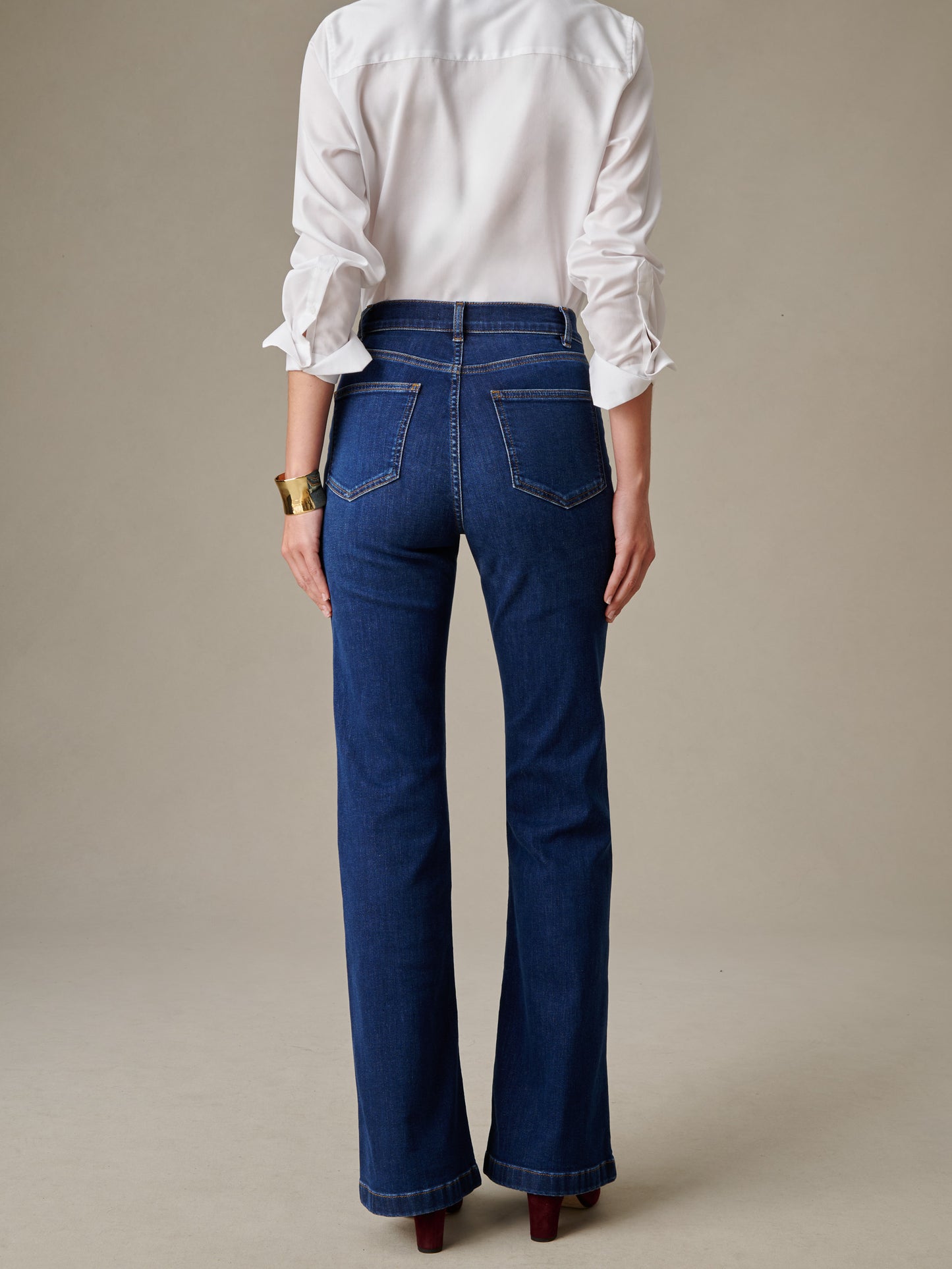 Rear view of a person wearing Domino Jeans by J.McLaughlin paired with a crisp white shirt and gold bracelet, showcasing a timeless, classic look with enduring style and craftsmanship.