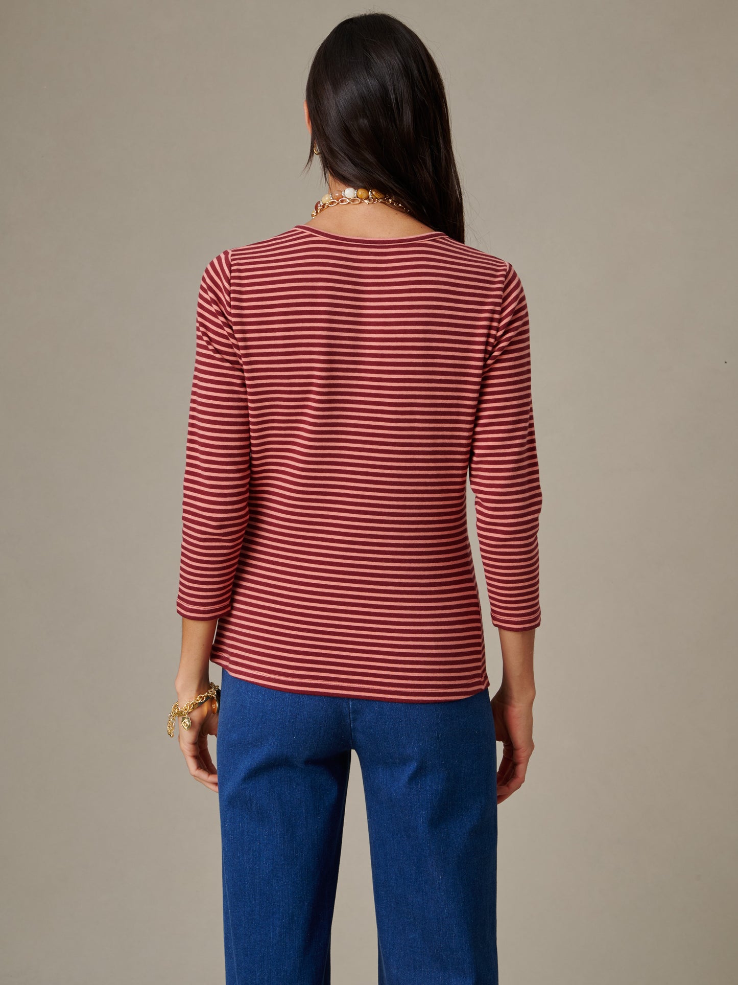 Woman wearing a red and white striped long sleeve top viewed from the back paired with blue jeans, showcasing the Sinclair Henley in Stripe by J.McLaughlin.